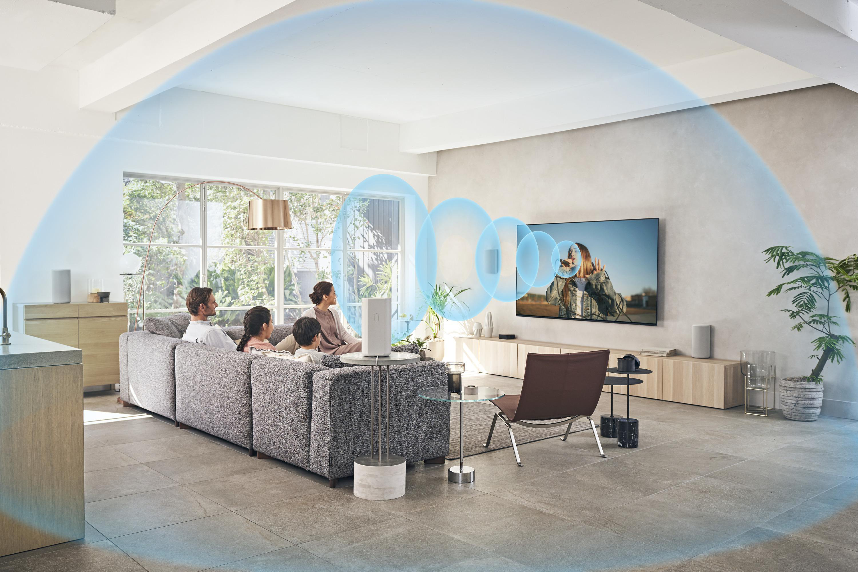 Menschen in einem Wohnzimmer mit Fernseher und Lautsprechern.