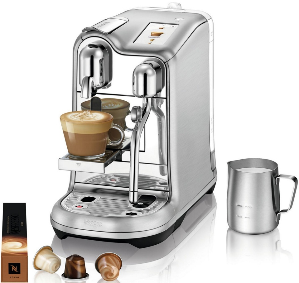 Eine silberne Kaffeemaschine mit einer Tasse Kaffee, Kaffeekapseln und einem Milchkännchen.