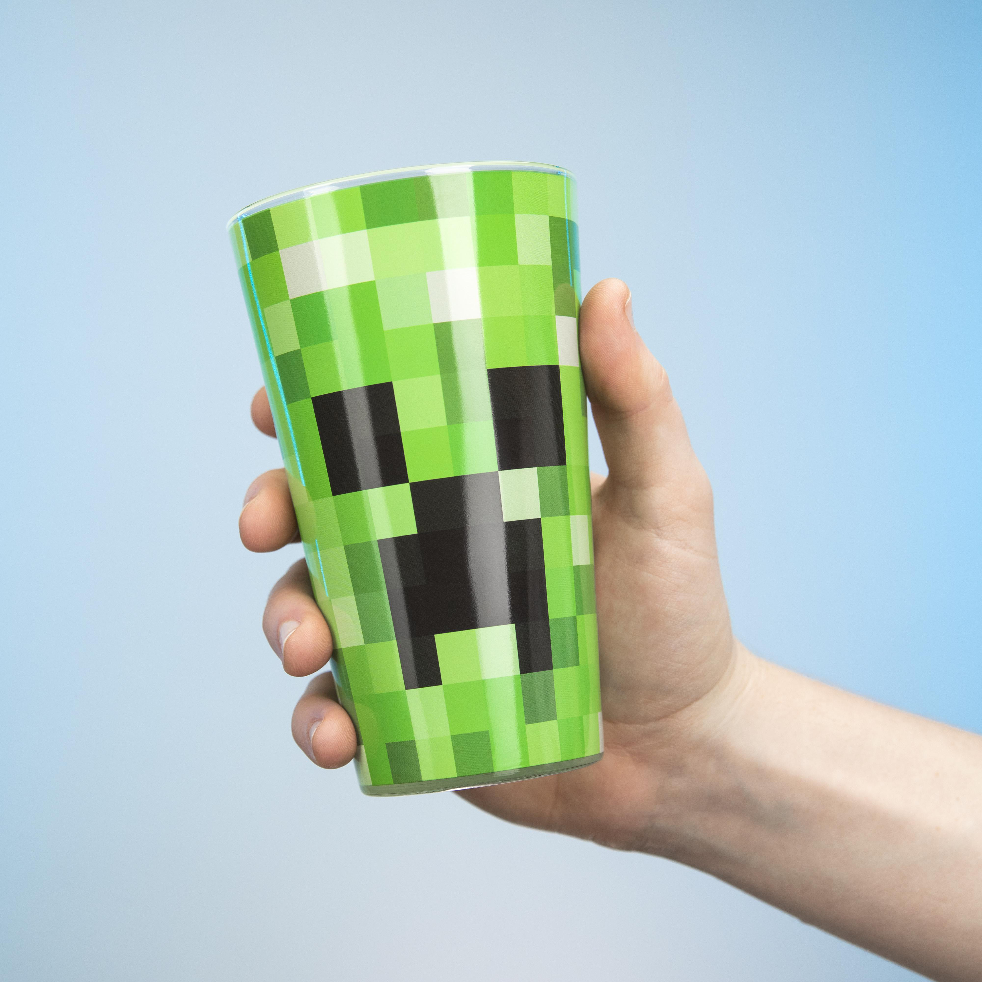 Ein grüner Becher im Minecraft-Stil, der in einer Hand vor einem blauen Farbverlauf gehalten wird.