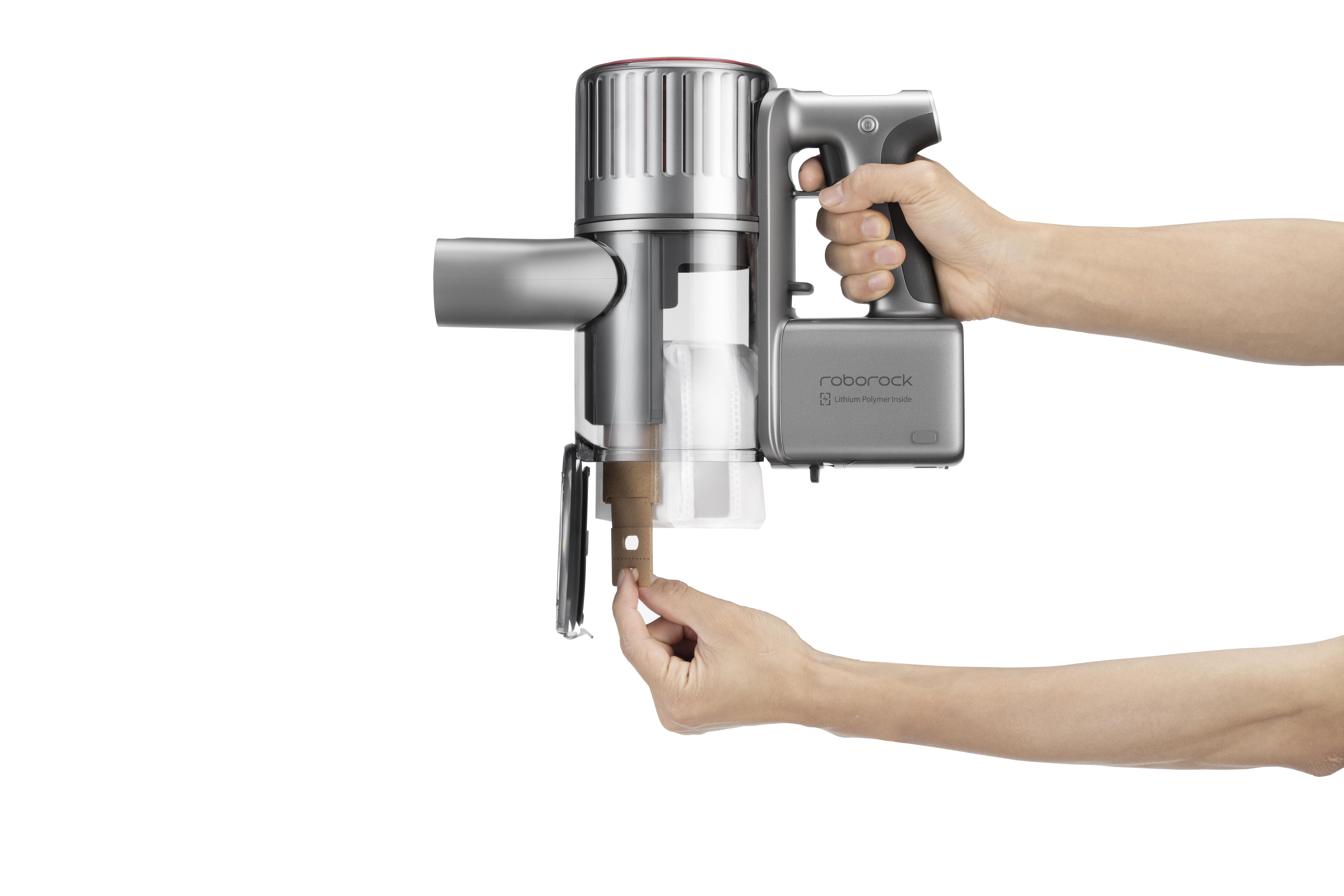 Eine Hand, die einen silber-grauen Staubsauger mit braunem Aufsatz hält.