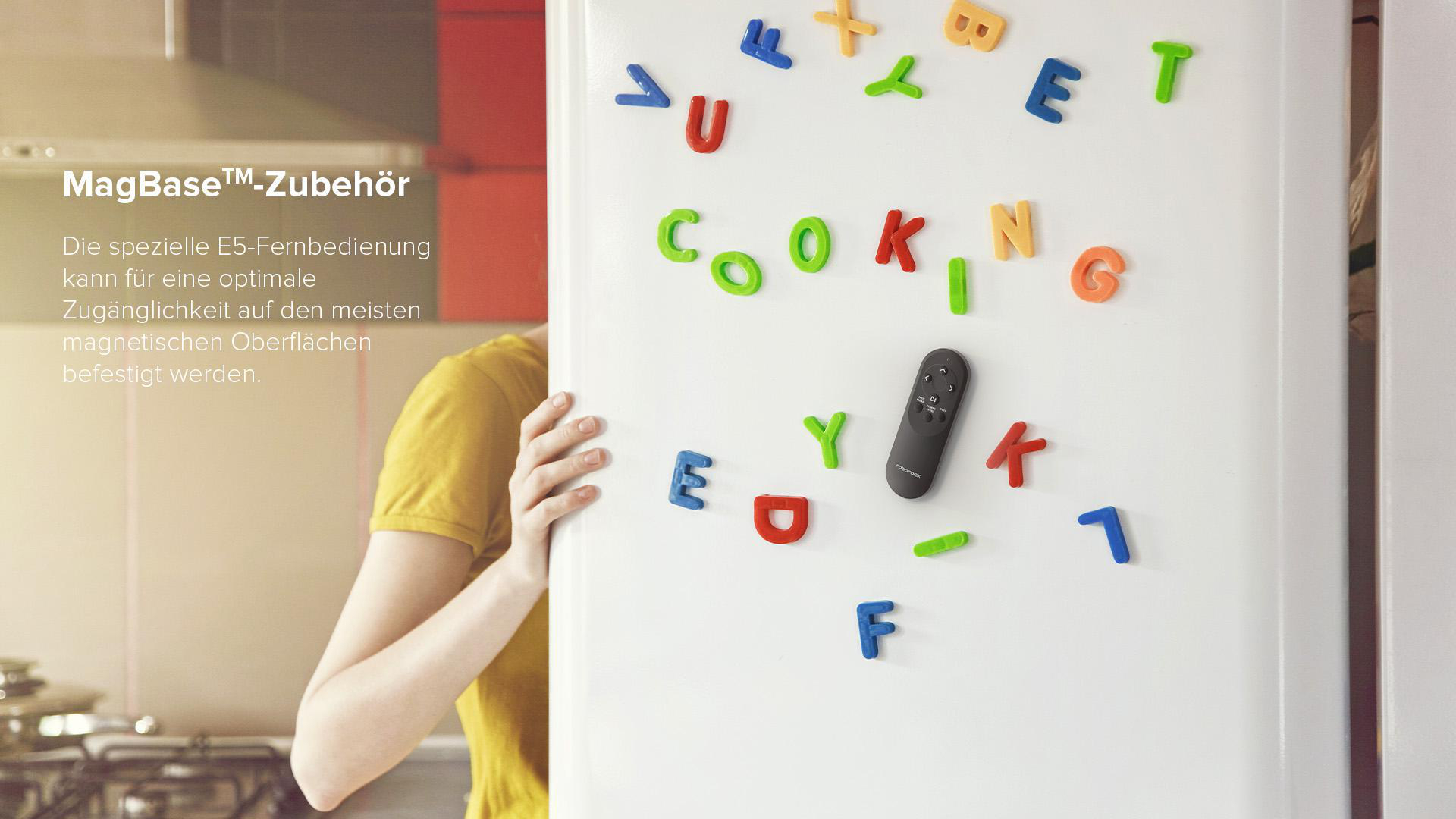 Eine Person mit gelbem Hemd neben einem Kühlschrank mit Buchstabenmagneten.