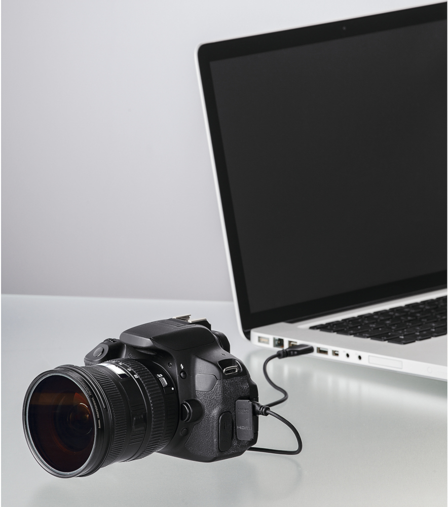 Een DSLR-camera aangesloten op een laptop via een zwarte kabel.