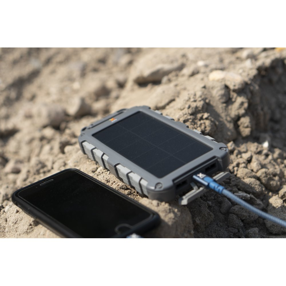 Solar-Ladegerät lädt ein schwarzes Smartphone auf felsiger Oberfläche auf.