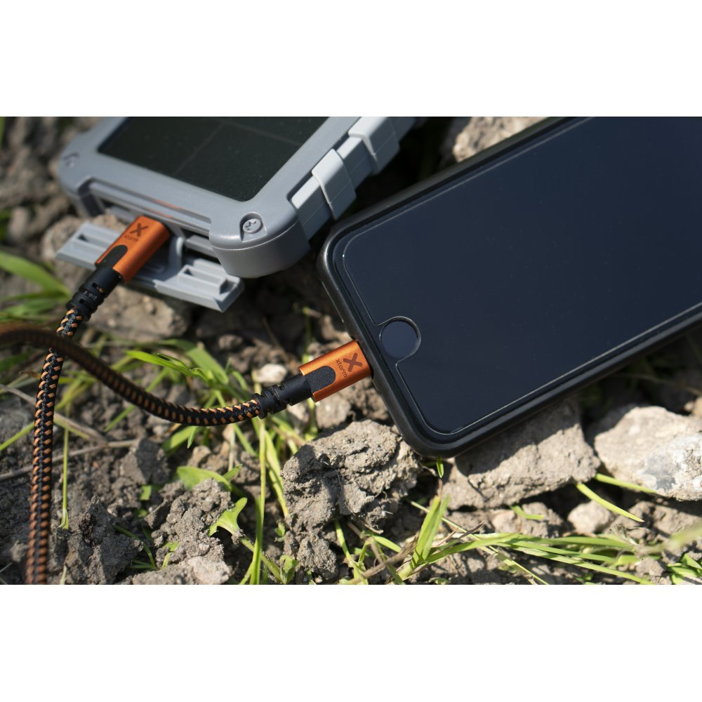 Ein Telefon, das von einem grauen Solarladegerät geladen wird, verbunden durch ein schwarz-orangenes Kabel.