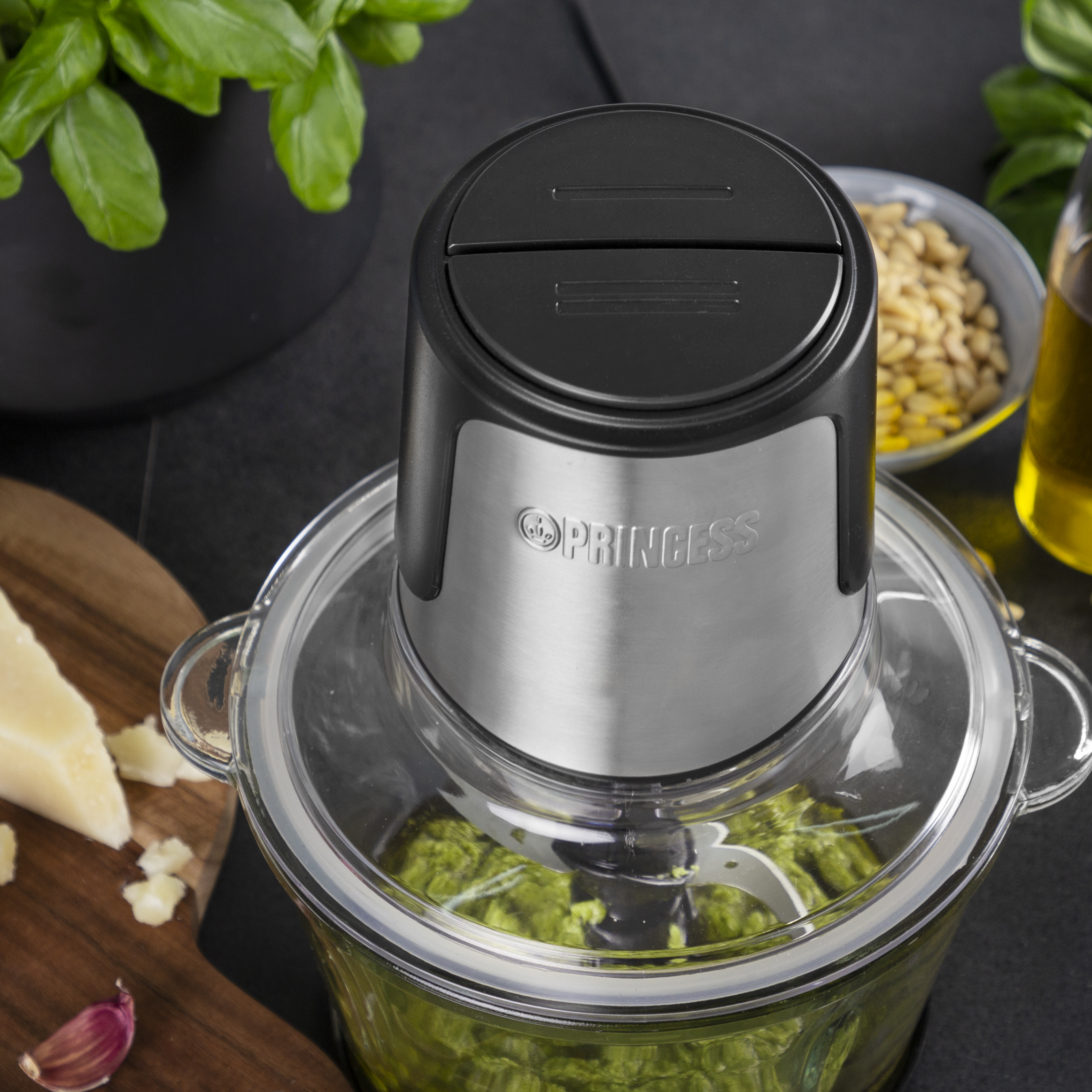 Keukenmachine met pesto erin en ingrediënten eromheen.