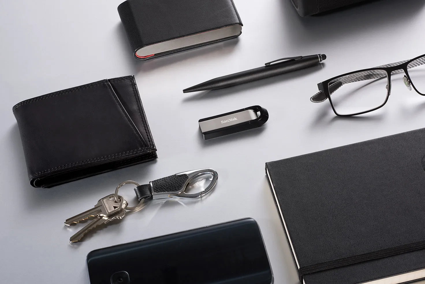 Assortiment d'accessoires de bureau, dont portefeuille, stylo, USB et lunettes.