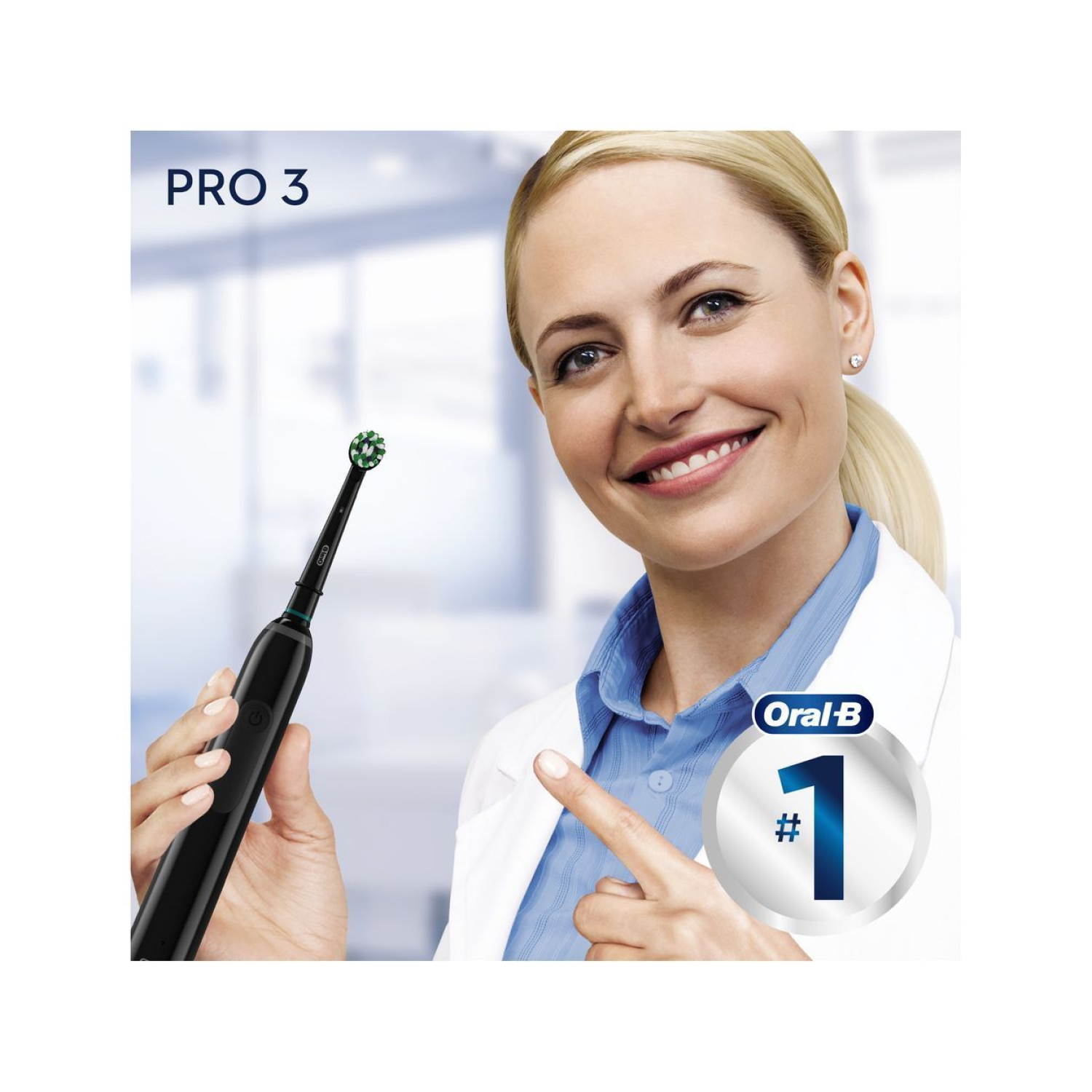 Mujer sonríe, señalando un cepillo Oral-B. El cepillo es negro con cabezal verde.