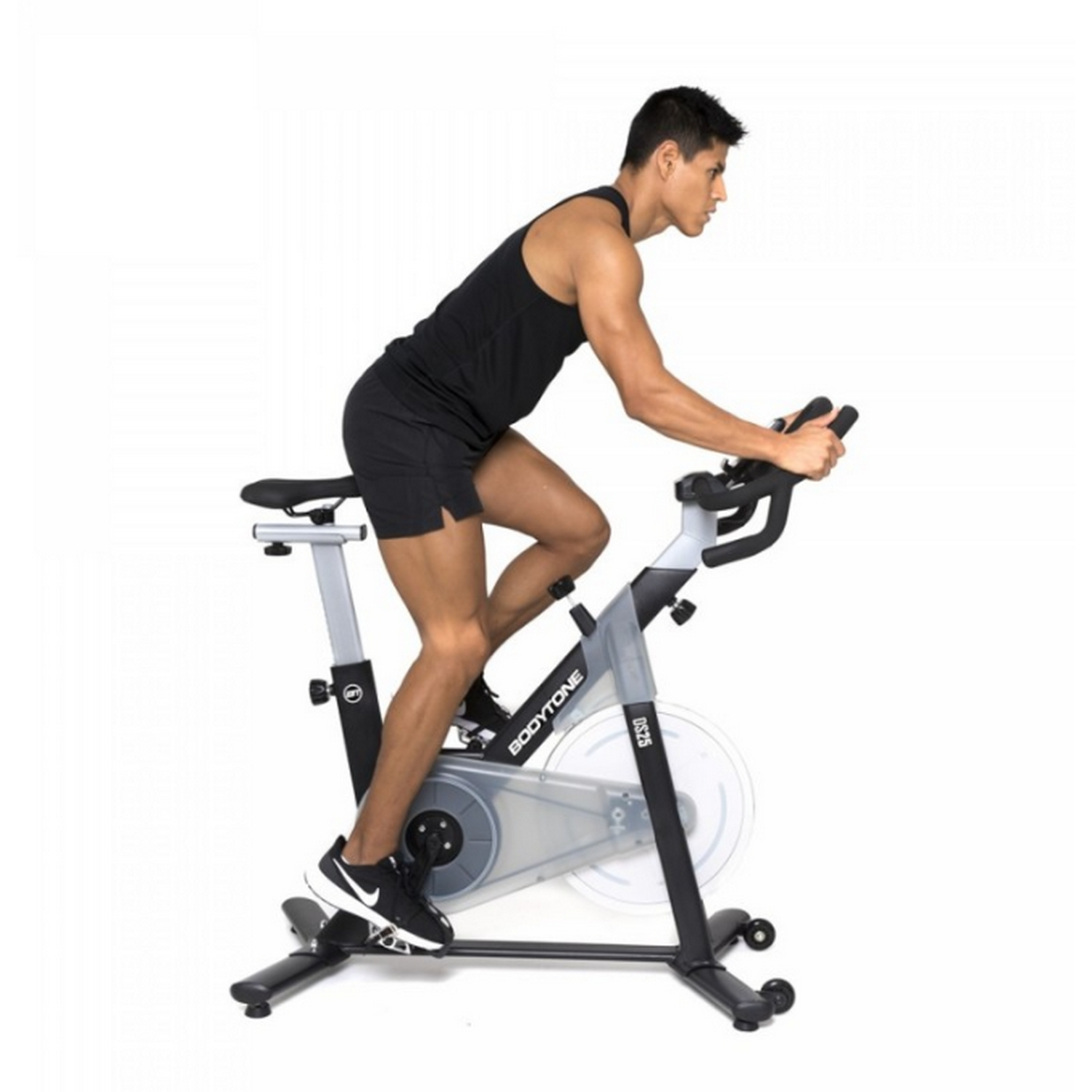 Hombre en una bicicleta estática, vistiendo ropa negra, en un gimnasio.