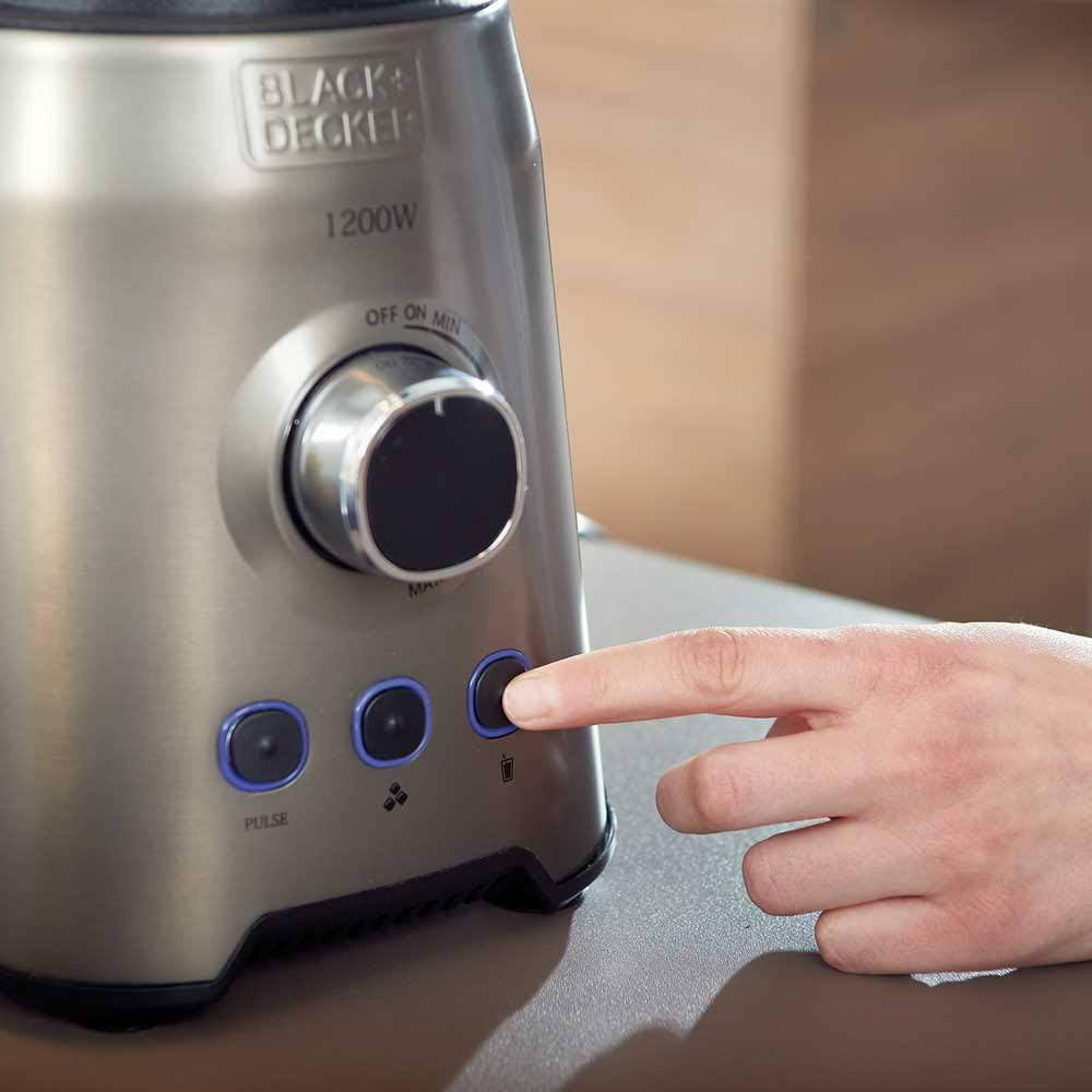 Mixer mit Hand, die einen Knopf drückt. Silbernes Gehäuse und schwarze Knöpfe mit blauen Lichtern.