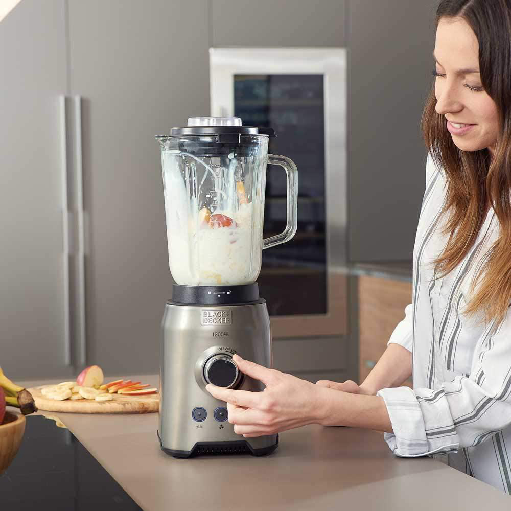 Frau benutzt einen silbernen Mixer. Küchenarbeitsplatte mit Zutaten. Black Decker Mixer.