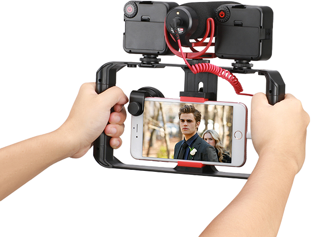 Kéz tart egy okostelefont egy filmes állványban. A telefonon egy filmes jelenet látható.
