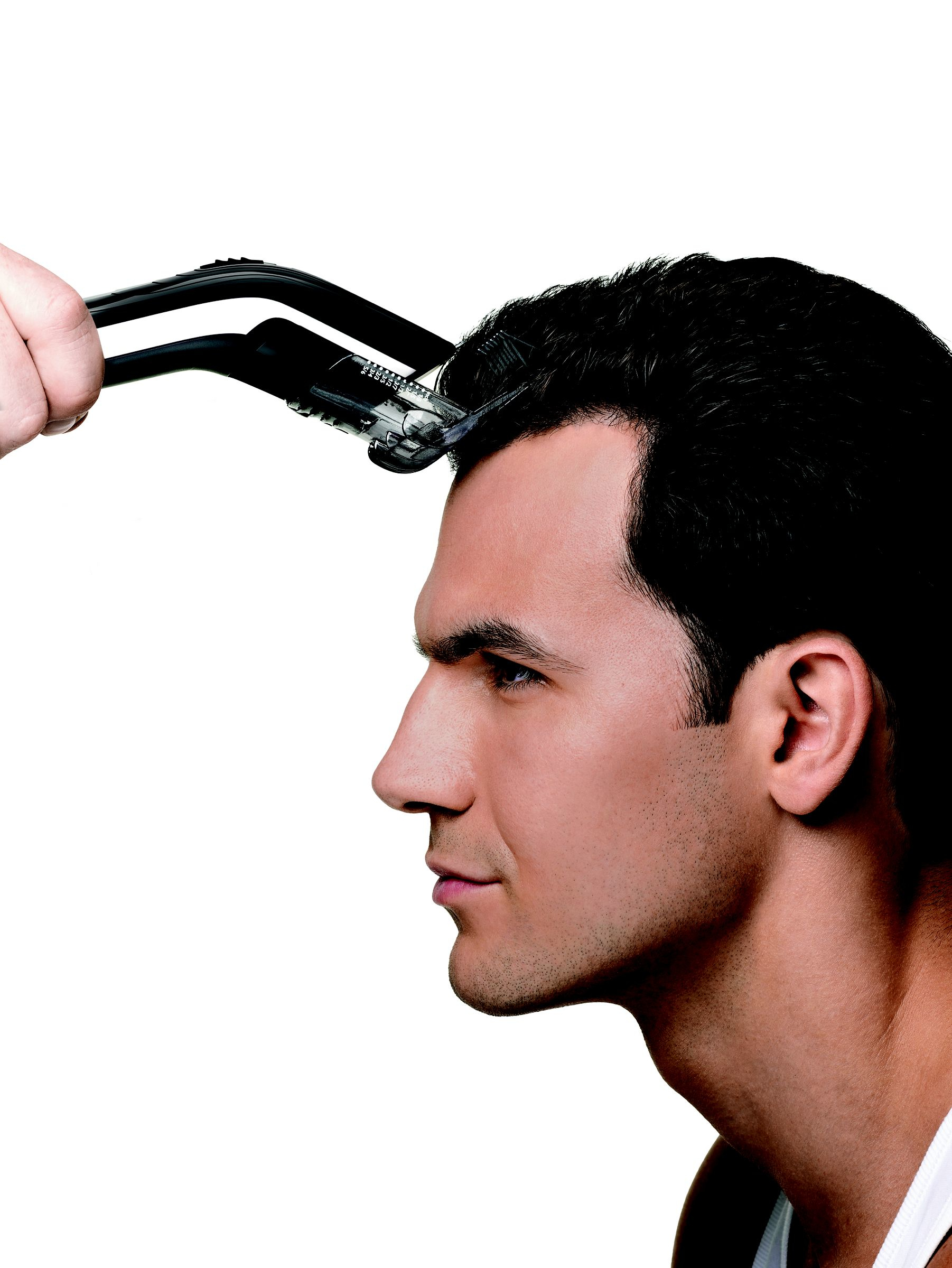 Un homme se fait couper les cheveux avec une tondeuse. La tondeuse est près du haut de sa tête.