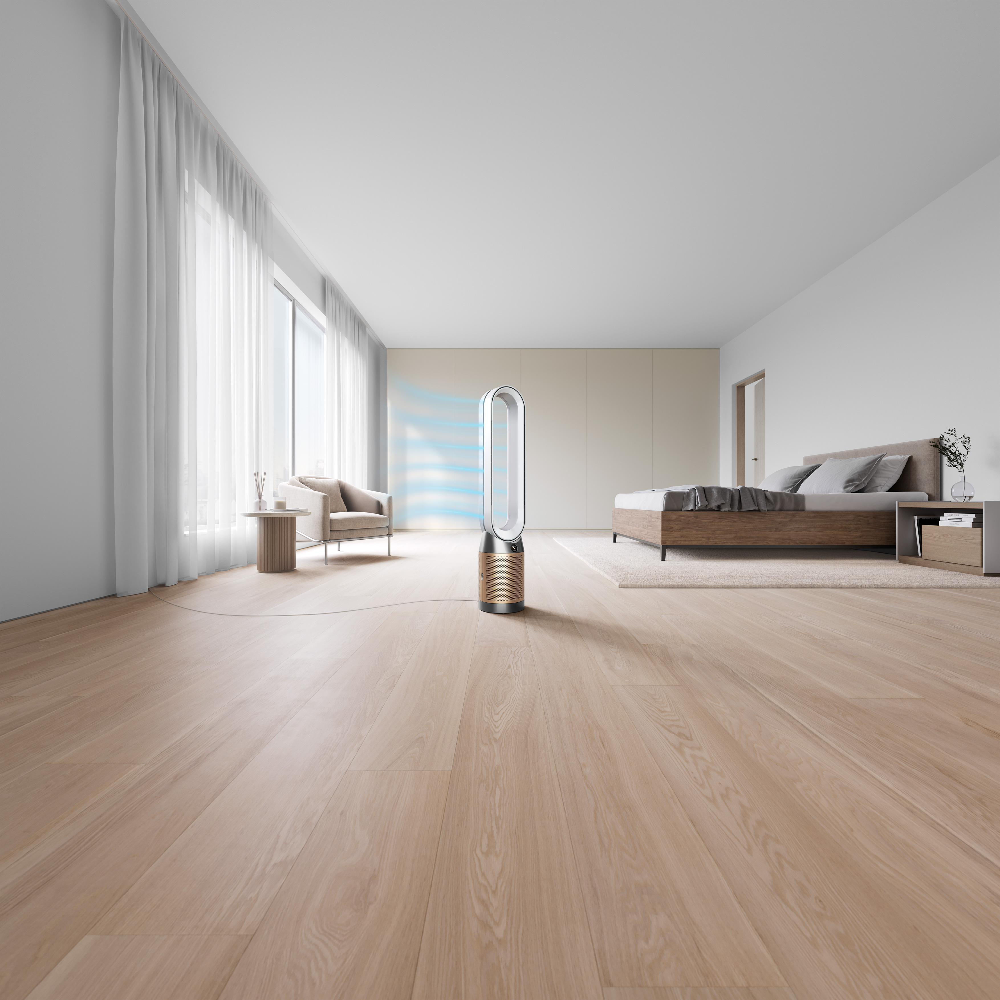 Ein moderner Ventilator in einem Schlafzimmer. Ein Bett, ein Stuhl und ein Fenster befinden sich ebenfalls im Raum. Der Boden ist Holz.