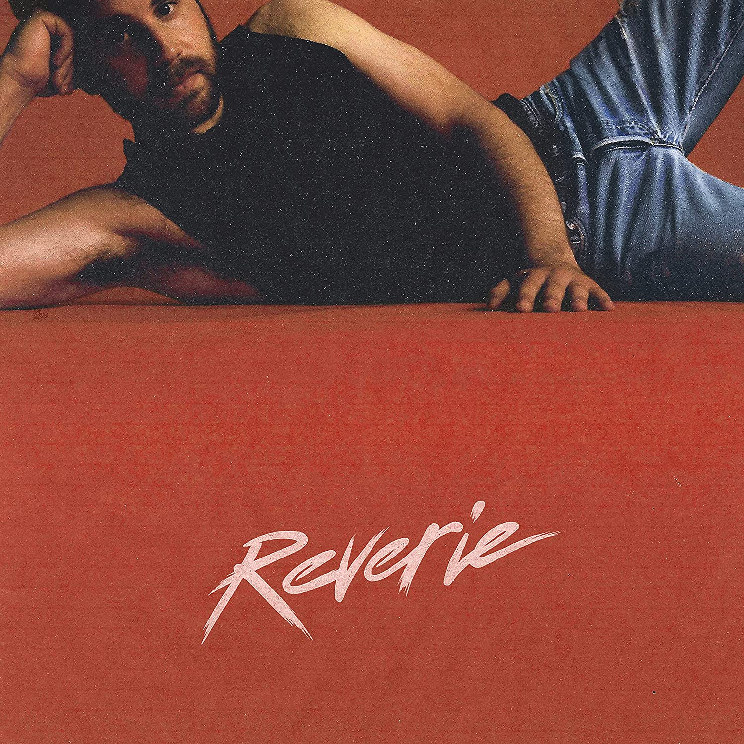 A 'Reverie' album borítója. Egy férfi fekszik egy piros felületen, fehér felirattal.