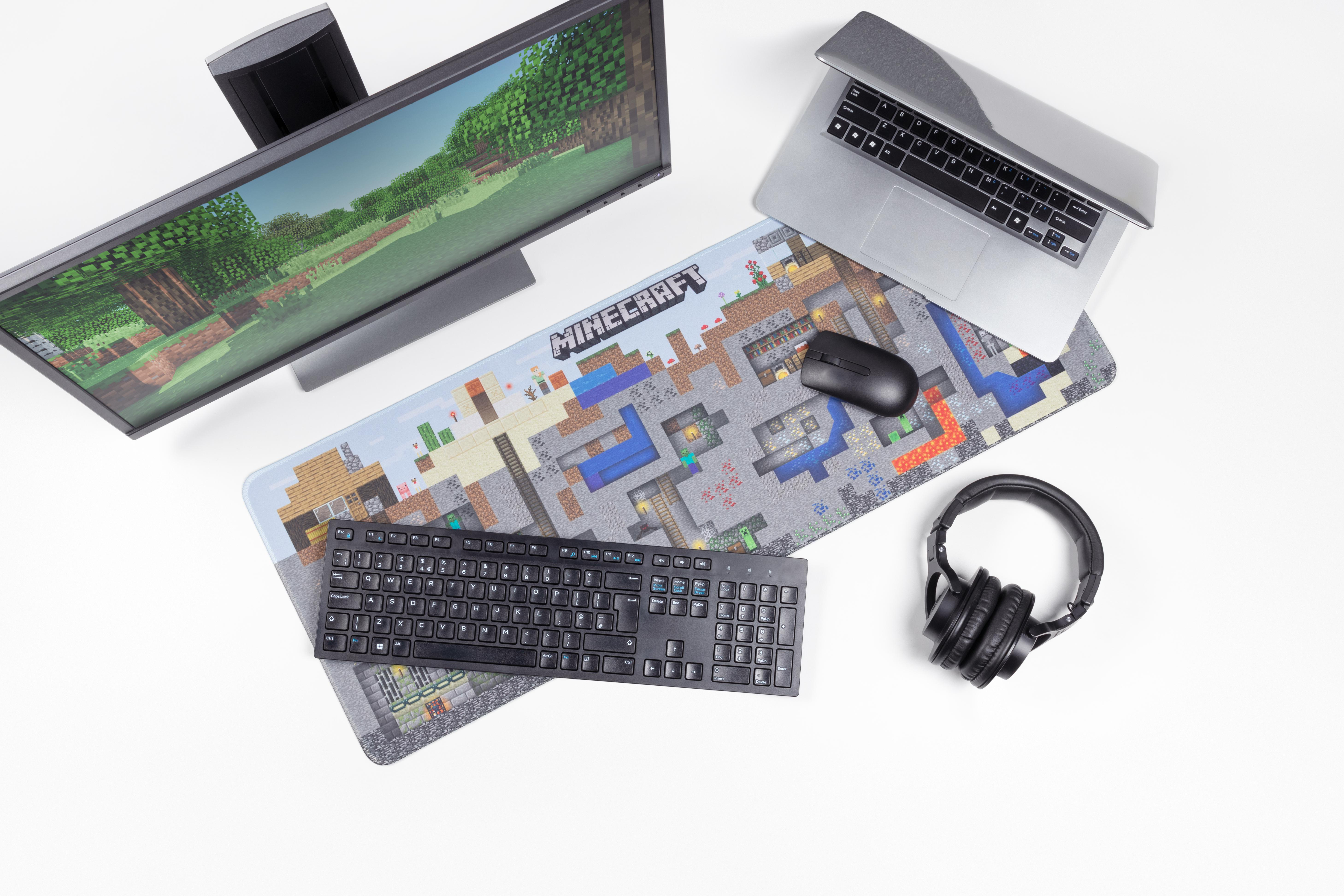 Gaming-Setup mit Monitor, Laptop, Maus, Tastatur und Headset auf Matte.