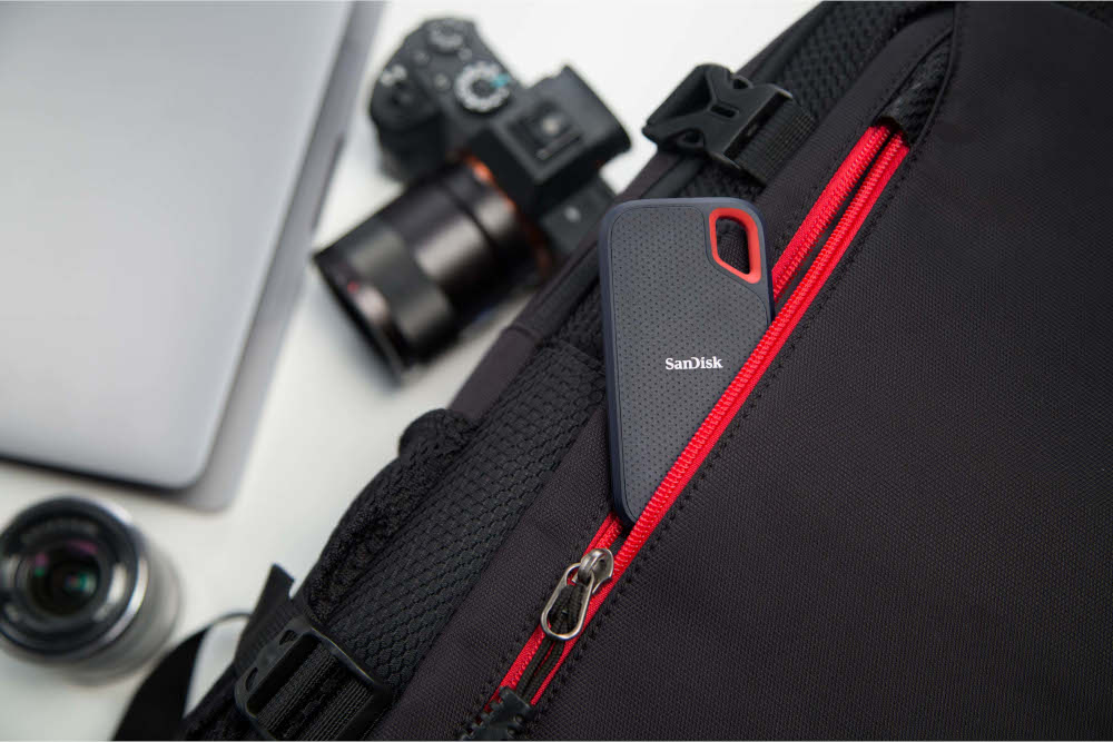Sac à dos noir avec un ordinateur portable, un appareil photo et un SSD portable SanDisk.