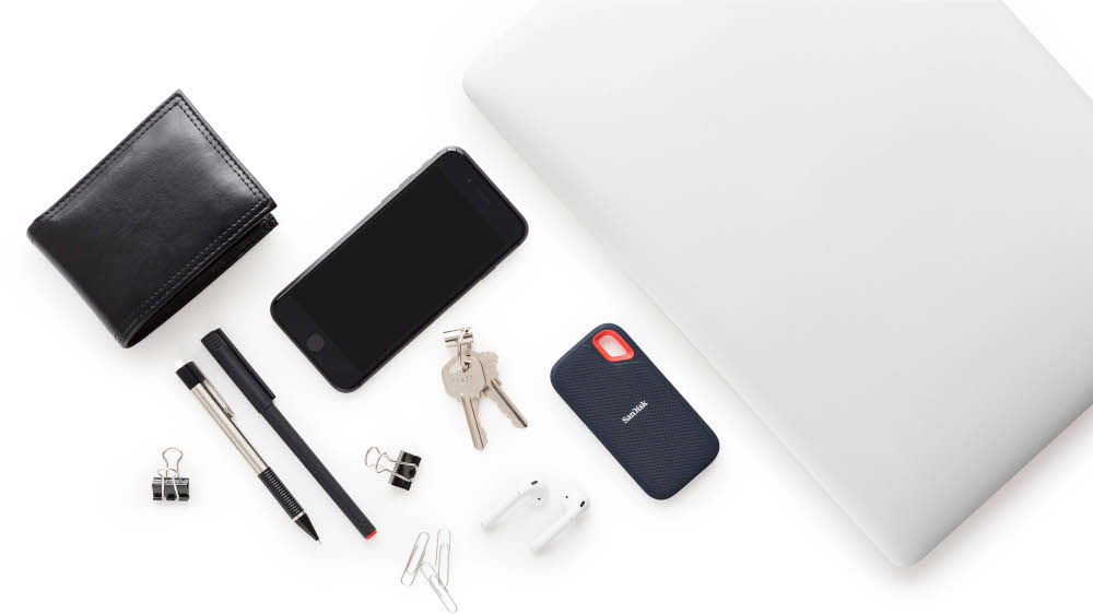 Portefeuille, stylos, téléphone, clés, écouteurs et ordinateur portable sur surface blanche, vue de dessus.
