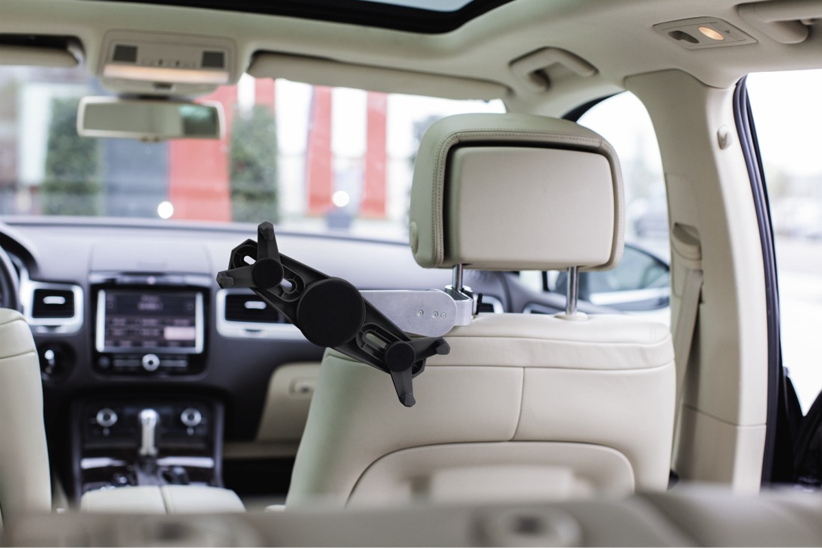 Un appui-tête de voiture avec un support de tablette attaché. L'intérieur de la voiture est visible.