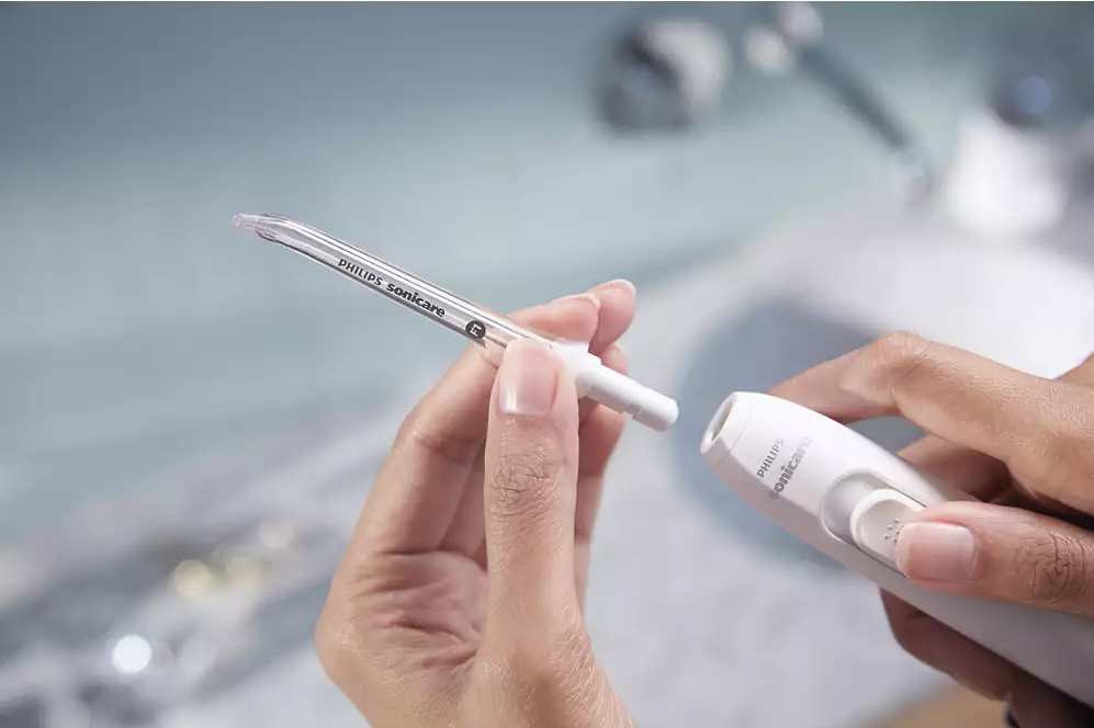 Hände halten weißes und transparentes Philips Sonicare Gerät.
