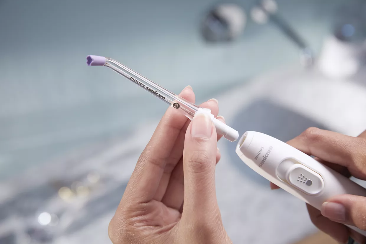 Hände, die einen weißen Philips Sonicare Wasserflosser zusammenbauen. Geräte- und Spitzenteile.