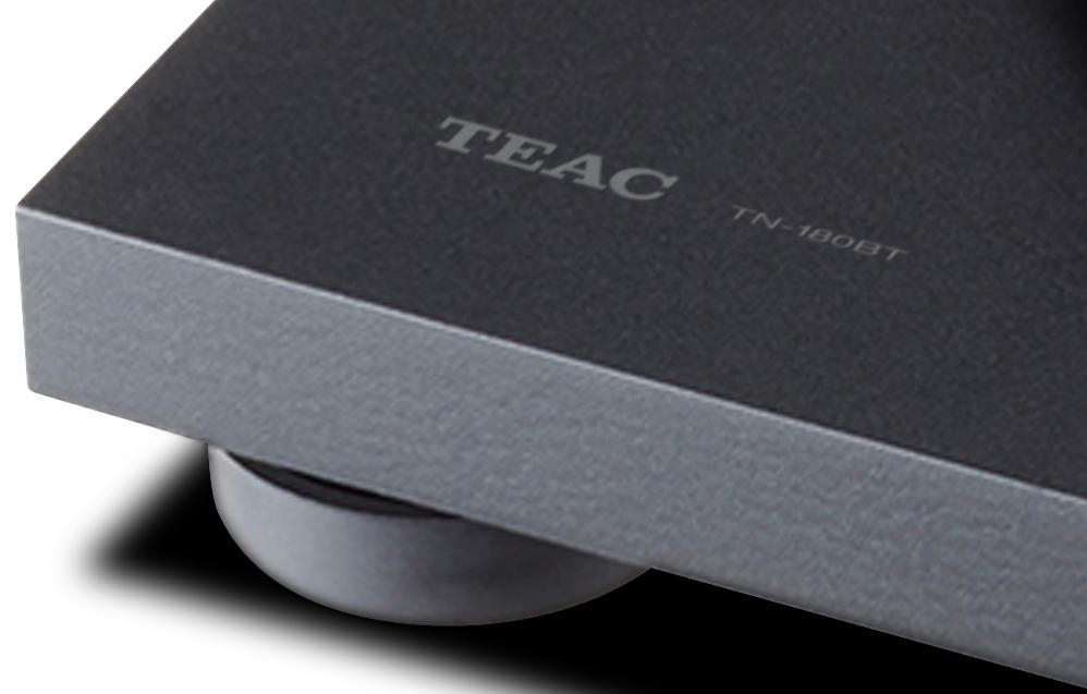 Nahaufnahme eines schwarzen Plattenspieler-Sockels mit 'TEAC' und 'TN-180BT' Text.