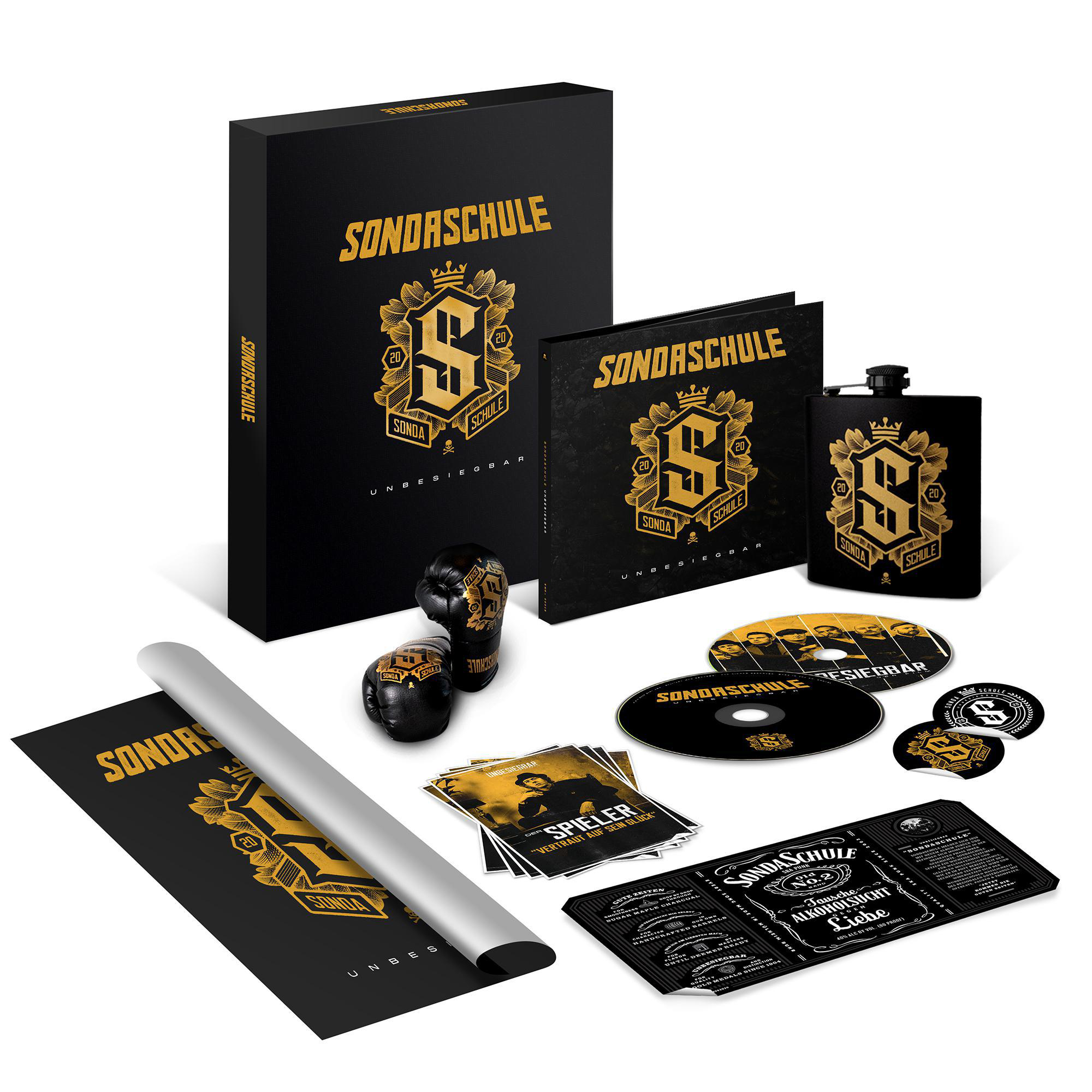 Eine Sammlung von schwarzem und goldenem SonderSchule-Merch, einschließlich einer Box und CDs.