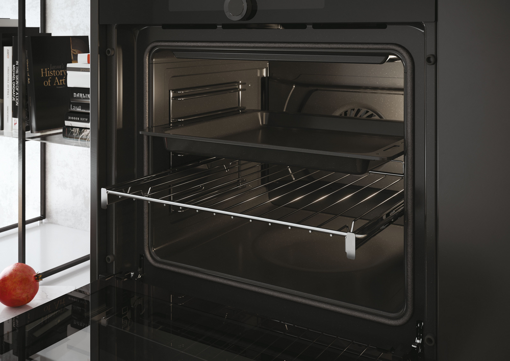 Un horno negro abierto. Hay dos rejillas y una bandeja para hornear en el interior.