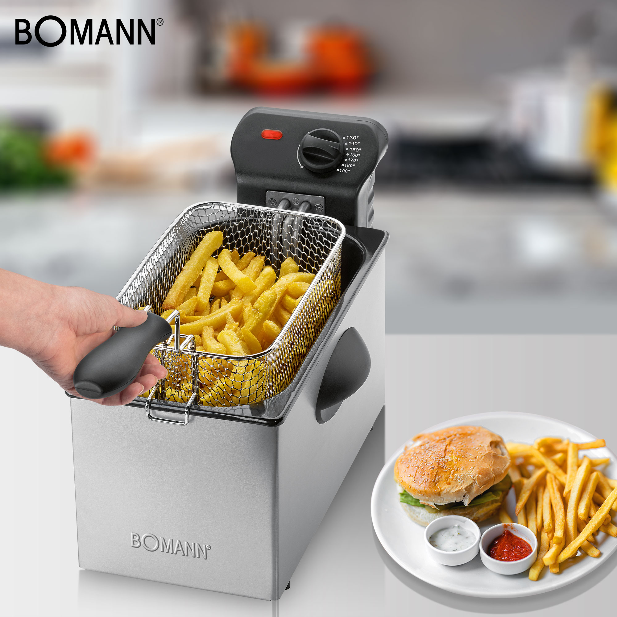 Eine Person hält einen Korb mit Pommes. Eine Fritteuse und ein Teller mit Burger und Pommes sind sichtbar.