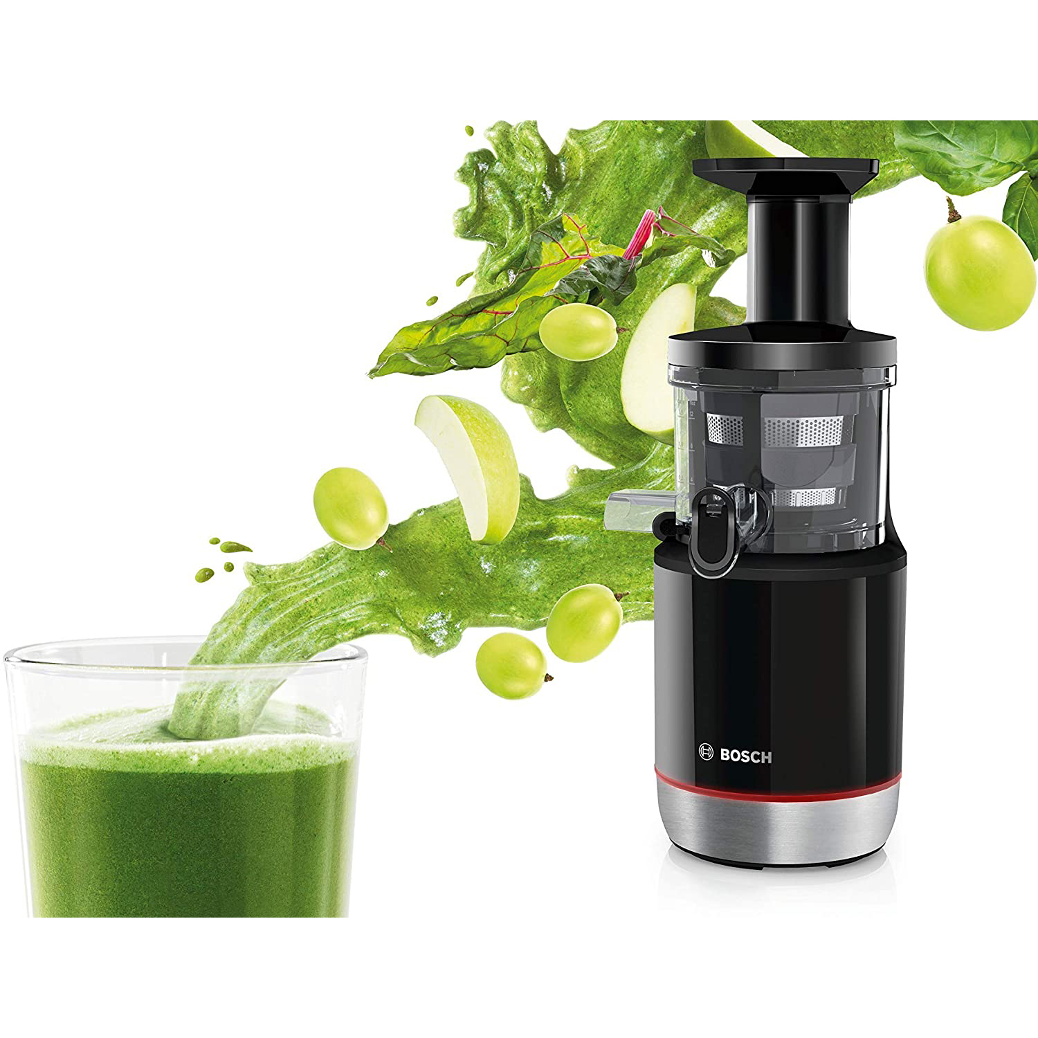 Una centrifuga nera e rossa versa succo verde in un bicchiere. Uva e frutta cadono.