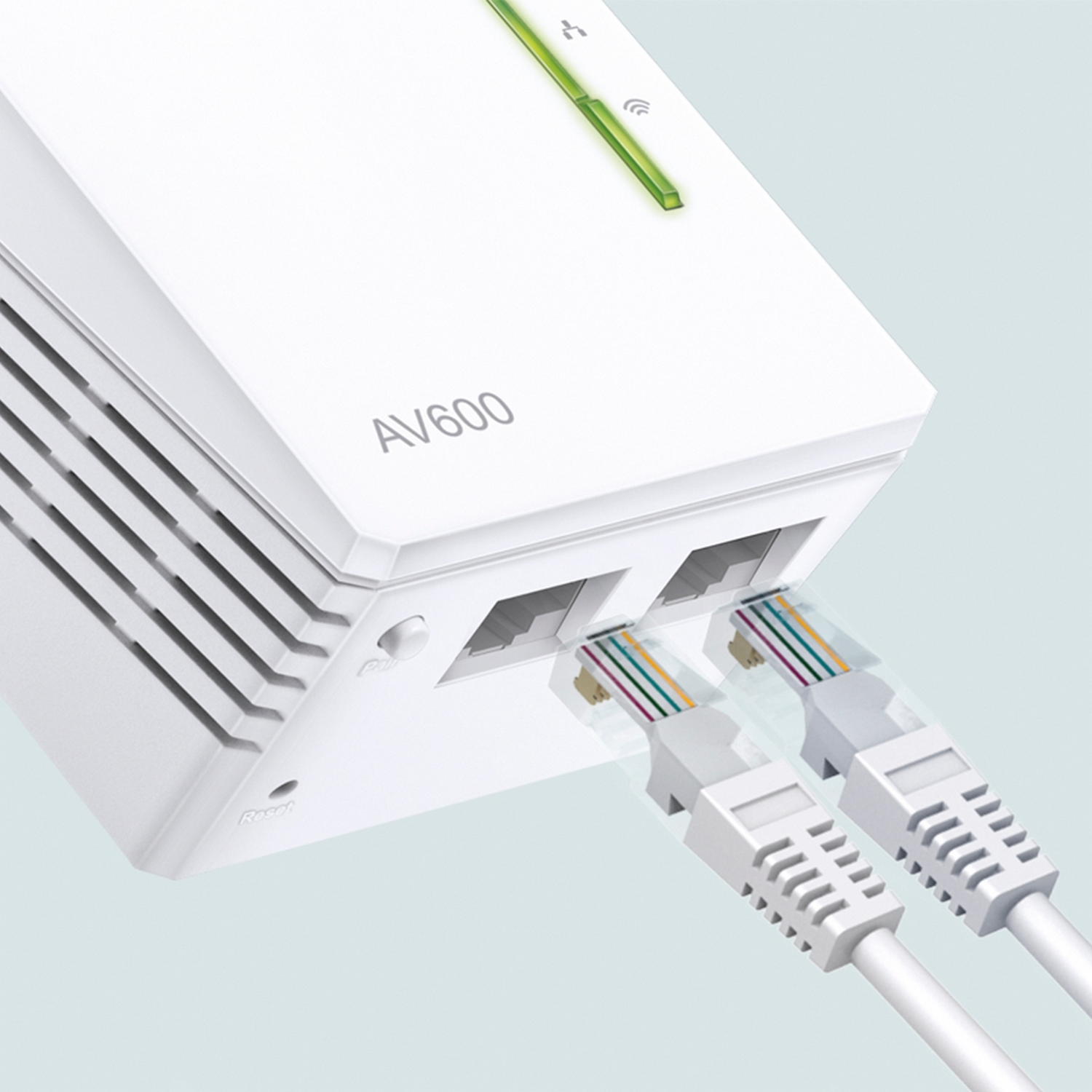 Primer plano de dos adaptadores tp-link AV600 Powerline blancos conectados con cables Ethernet.