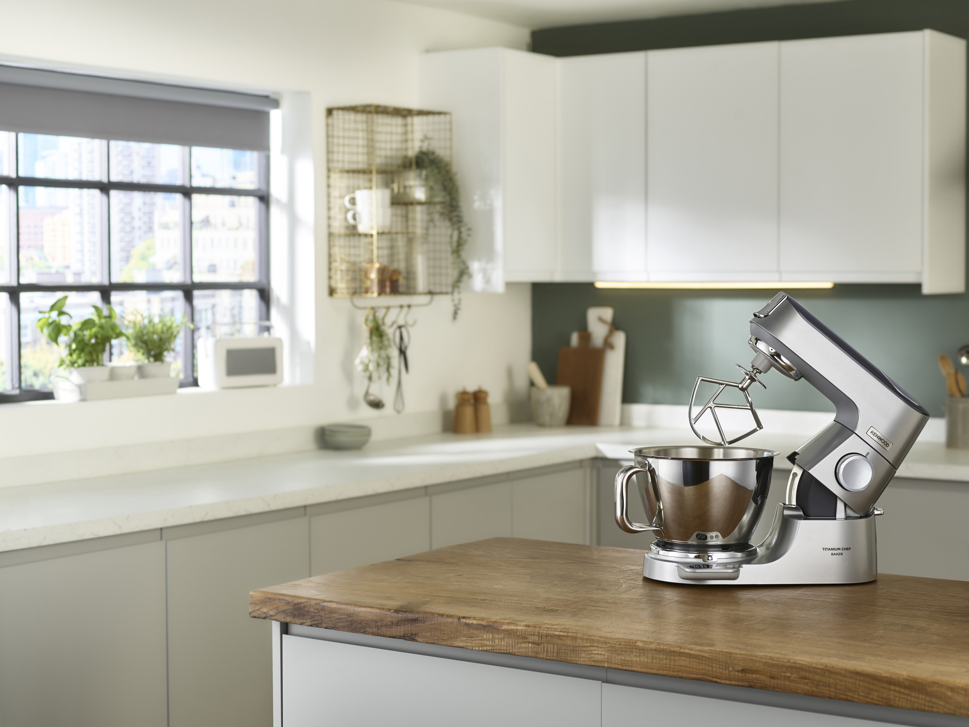 Küche mit silbernem Mixer auf einer Holztheke. Im Hintergrund ein Fenster und weiße Schränke.