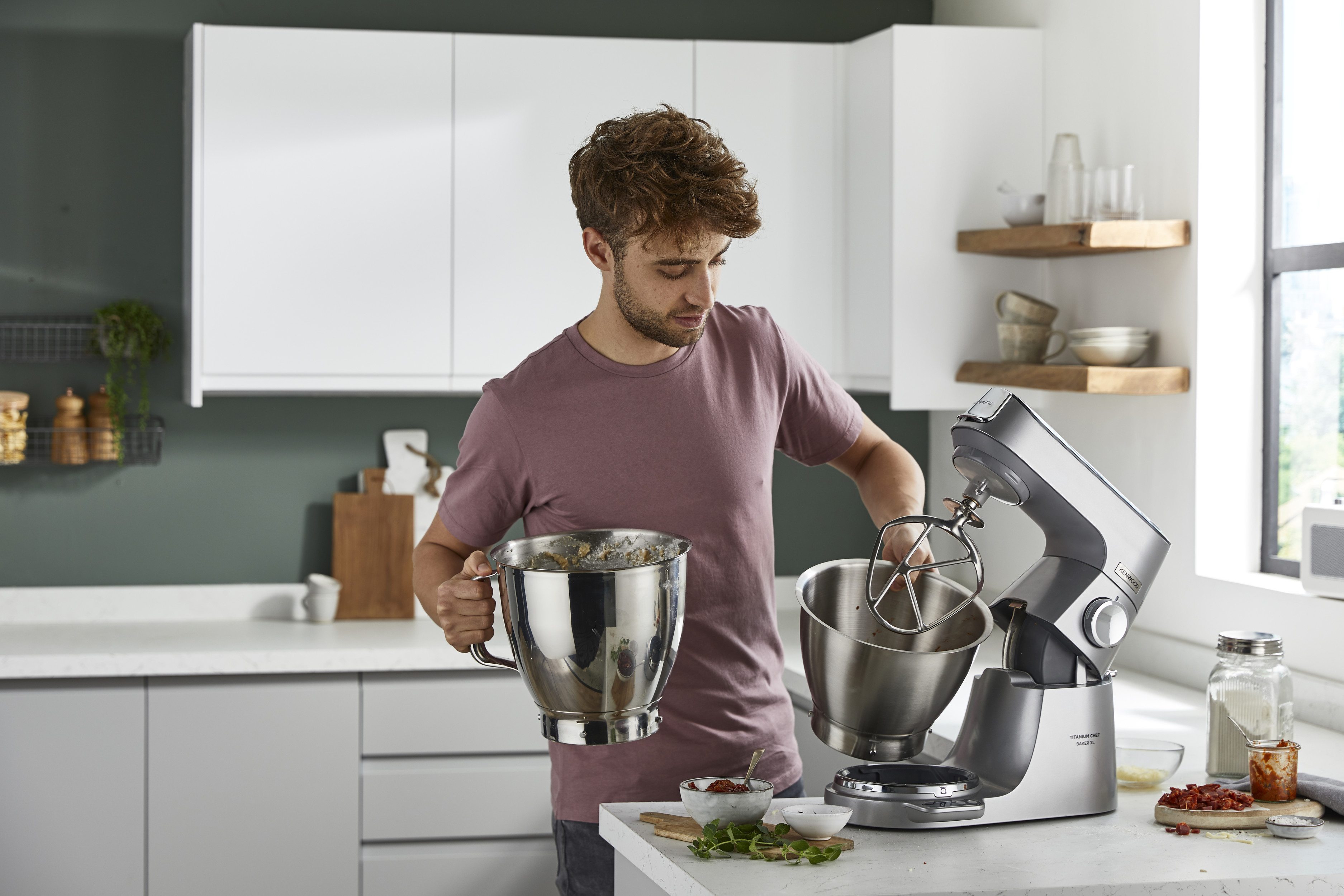 Ein Mann in einer Küche hält eine Rührschüssel und möchte einen Küchenmixer benutzen.
