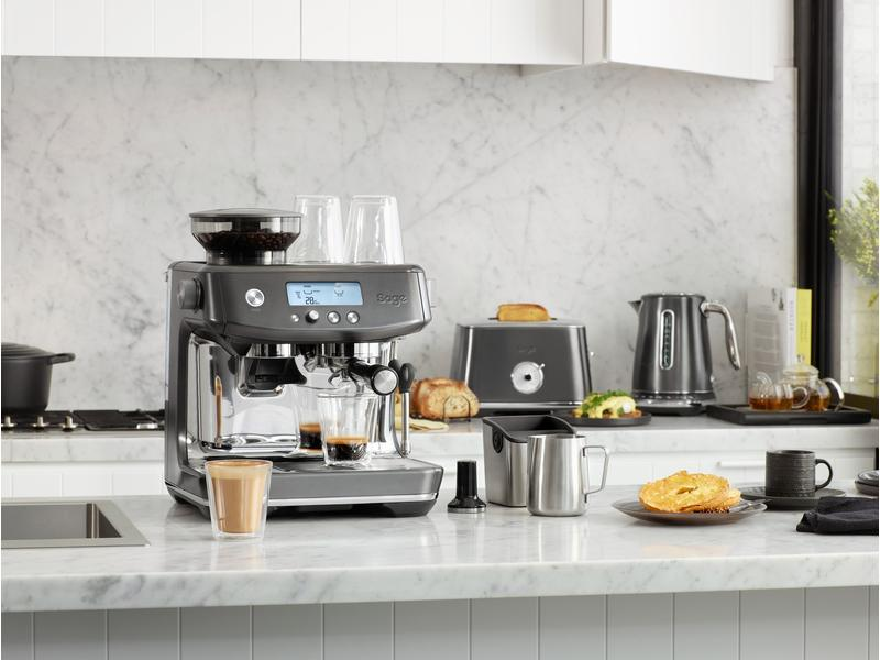 Un bancone della cucina con macchina da caffè, tostapane, bollitore e vari oggetti legati al caffè.
