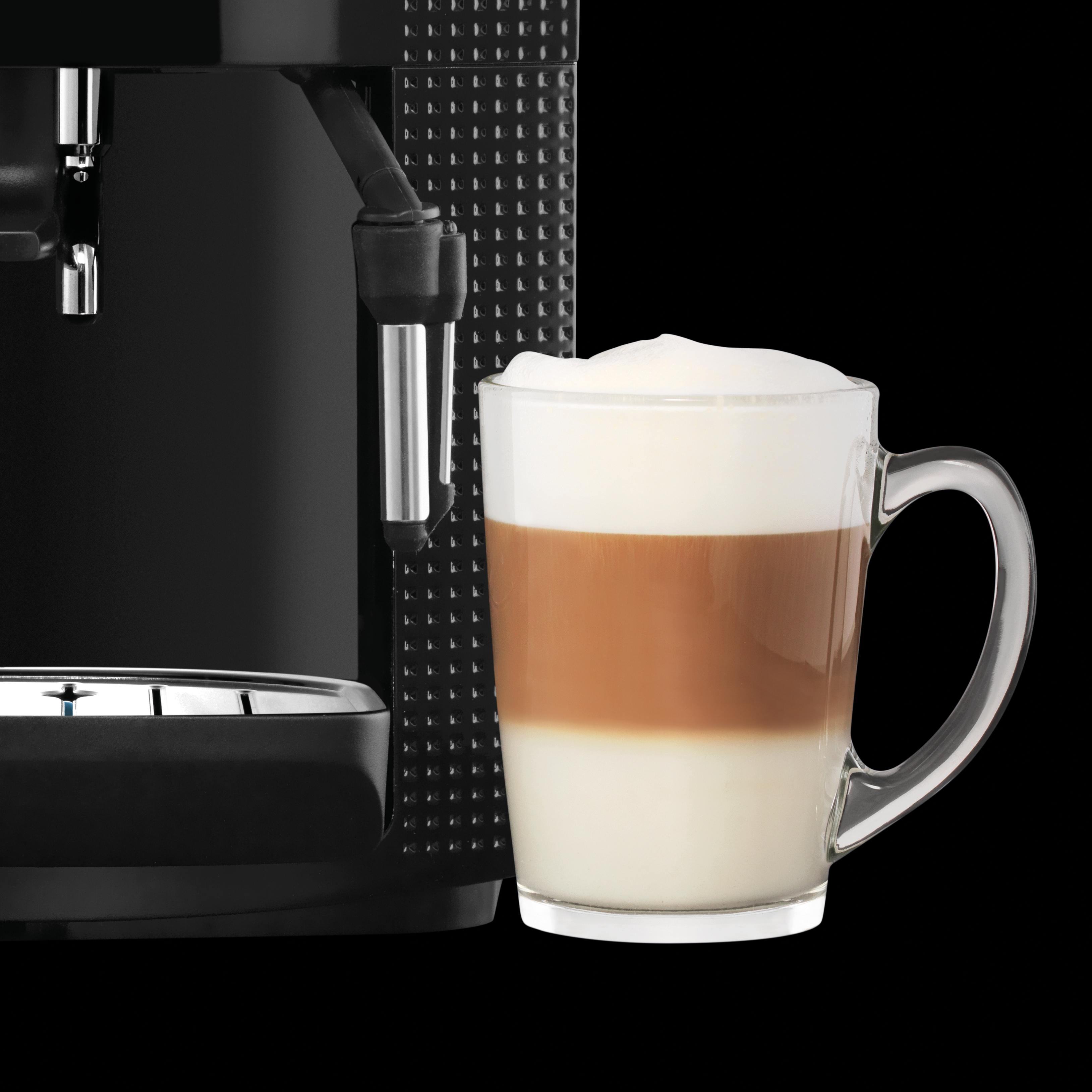 Egy fekete eszpresszó gép egy rétegzett latte-val teli átlátszó üvegpohár mellett, fekete háttérrel.