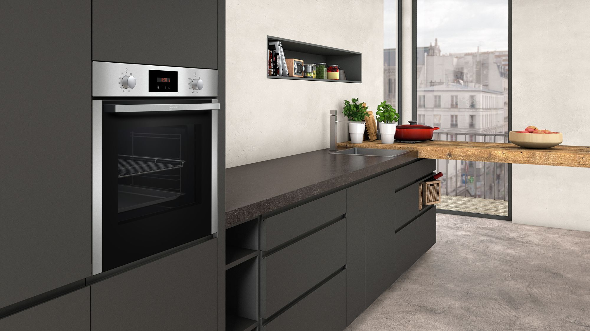 Eine moderne Küche mit Backofen und Schränken. Im Hintergrund ein Fenster mit Stadtblick.