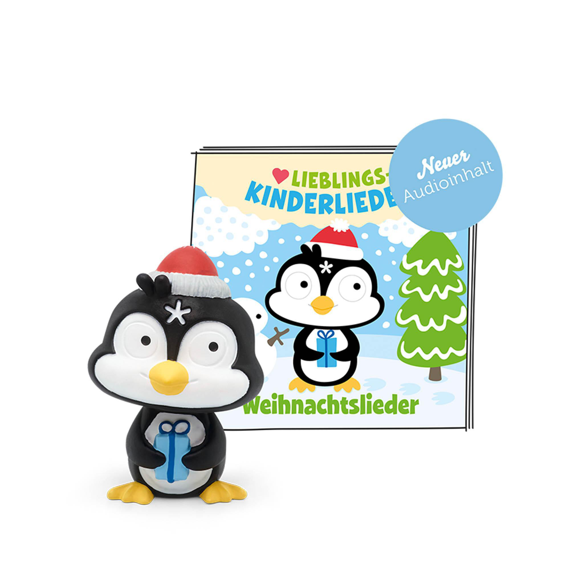 Ein Pinguin-Spielzeug mit Geschenk und einem Weihnachtsbuchcover. Schnee und Bäume im Hintergrund.