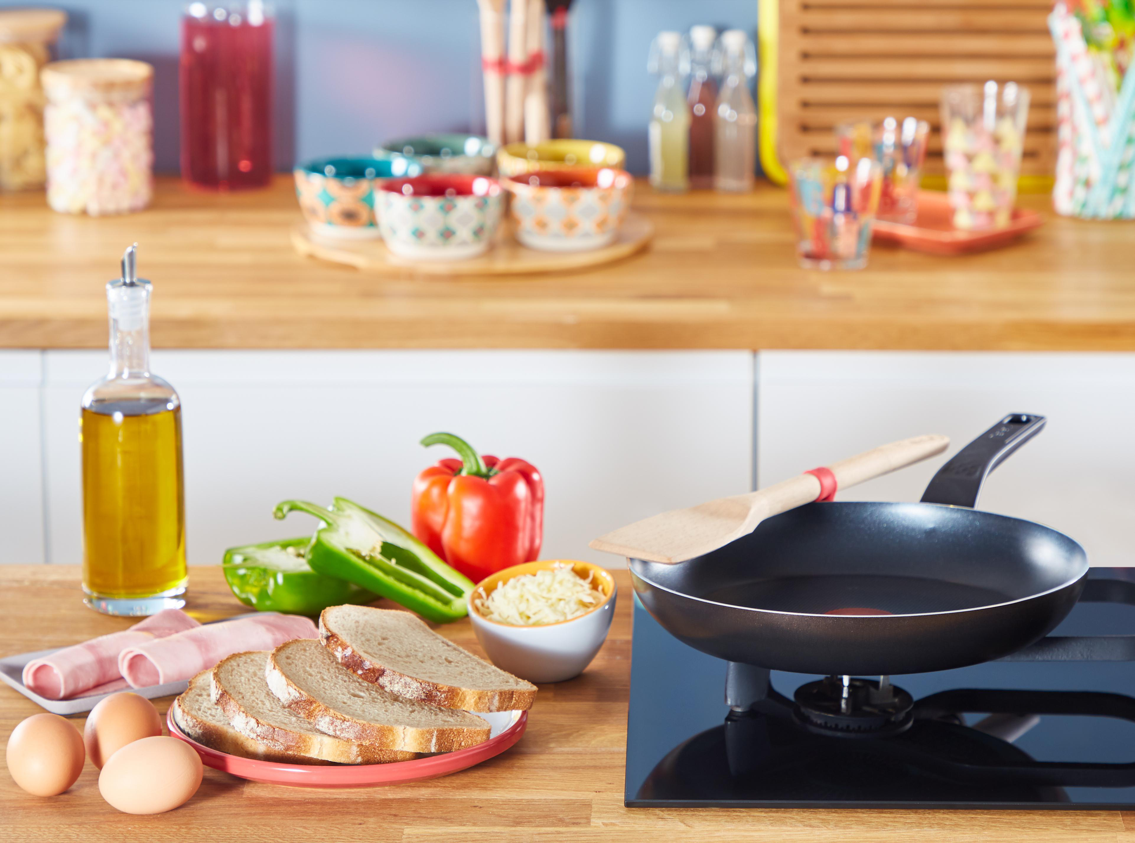 Eine Küchenszene mit Essen, Utensilien und Zutaten auf einer Holz-Arbeitsplatte.