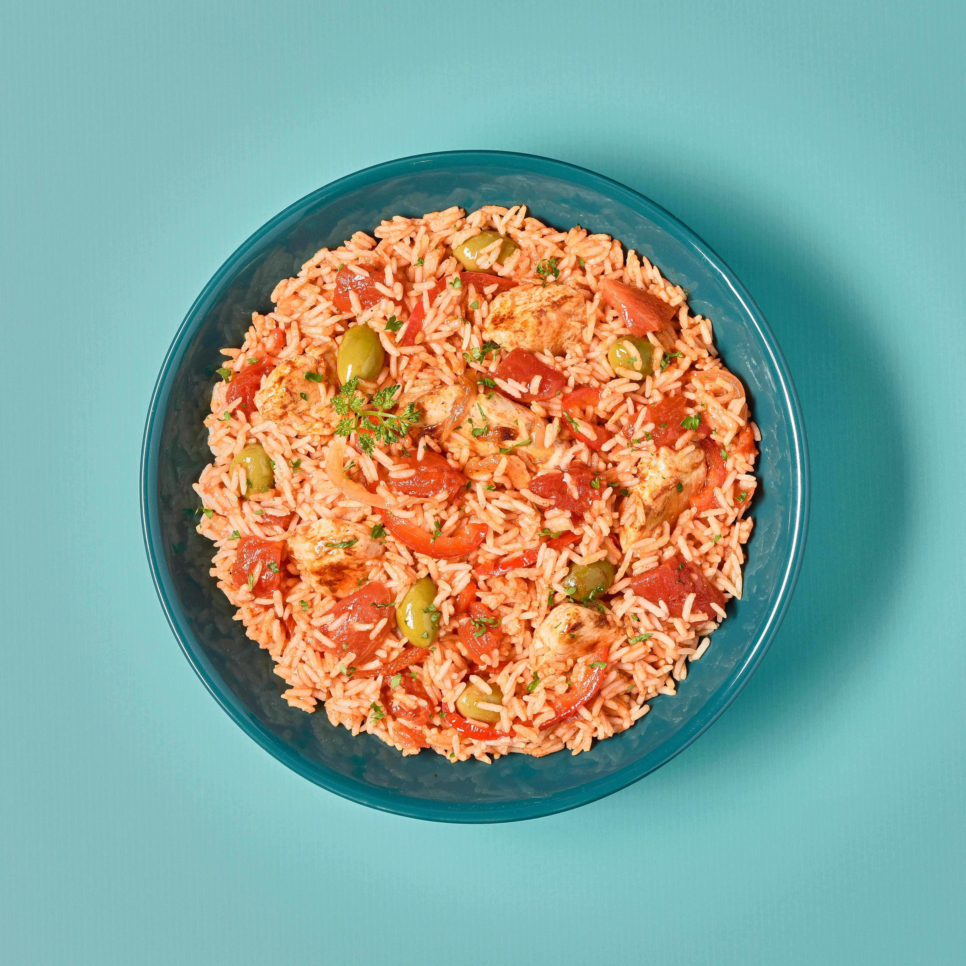 Reis mit Tomaten, Hühnchen und Oliven, in einer blauen Schüssel, Draufsicht.