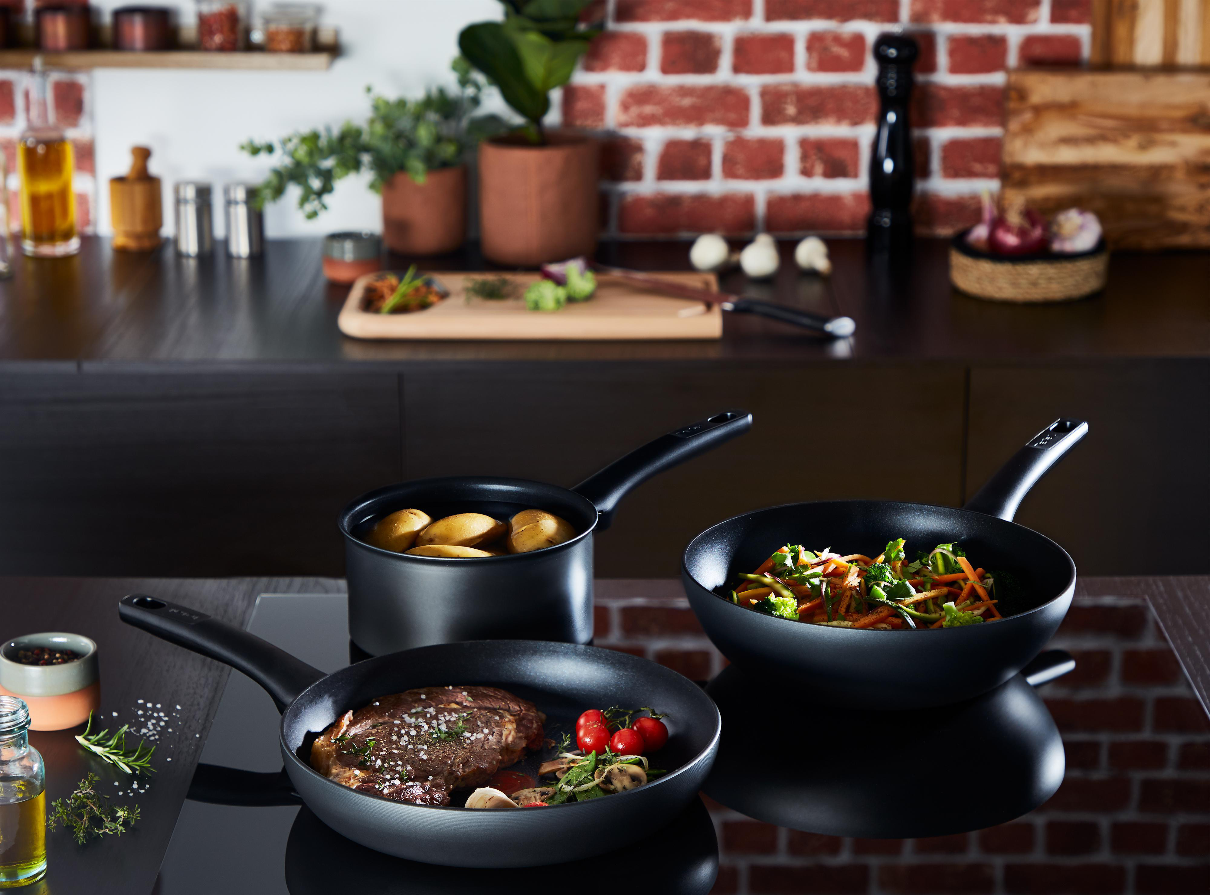 Küchenszene mit Pfannen und kochendem Essen.