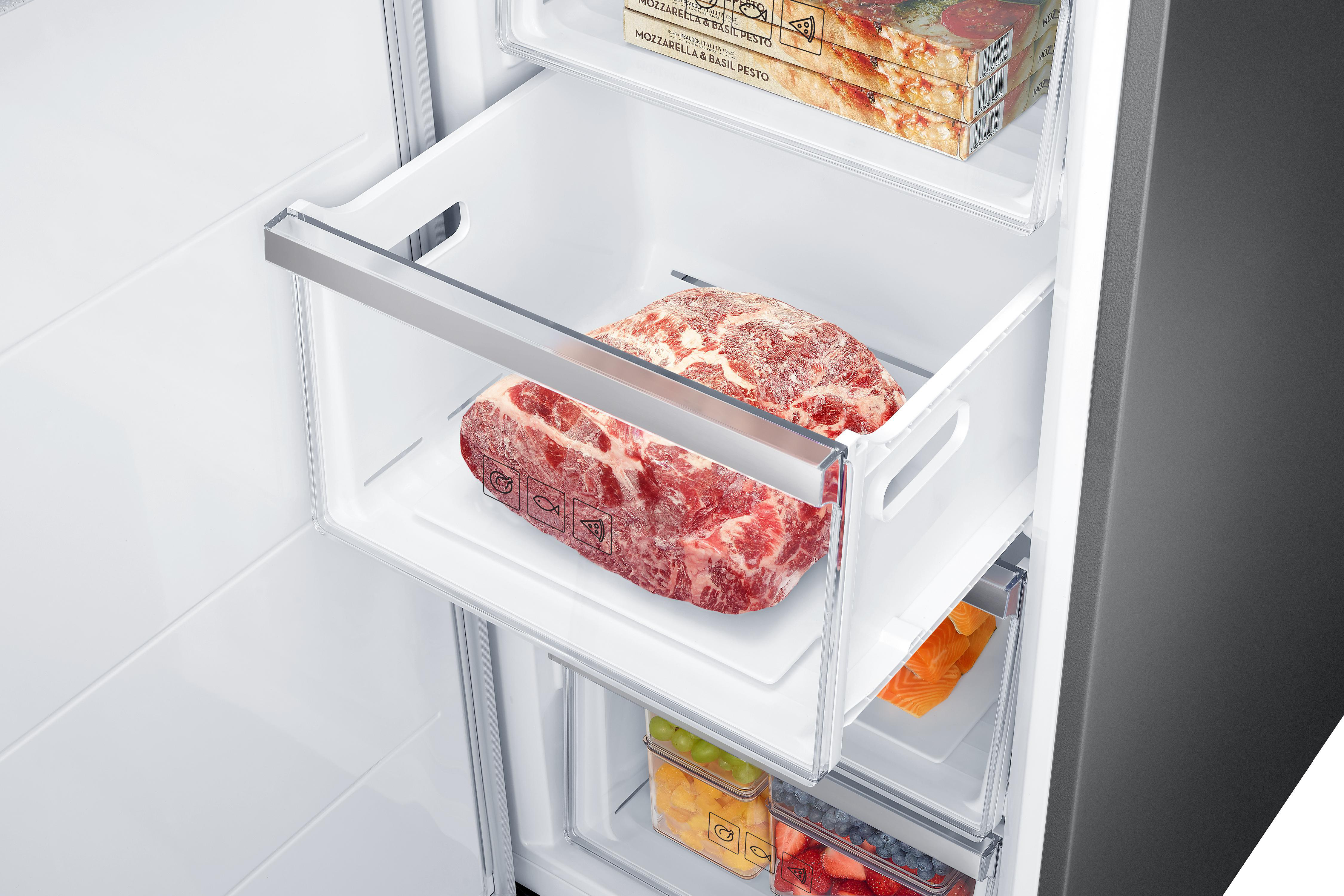 Kühlschrankinnenraum mit gefrorenem Fleisch und anderen Lebensmitteln. Fleisch in der Schublade. Andere Lebensmittel auf Regalen.