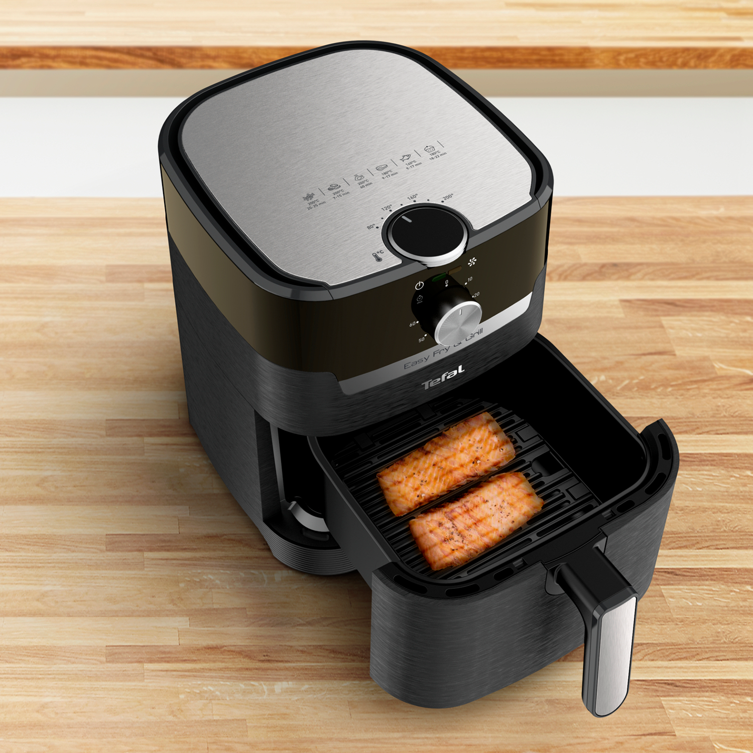 Zwarte en zilveren airfryer met open lade, toont twee stukken zalm.