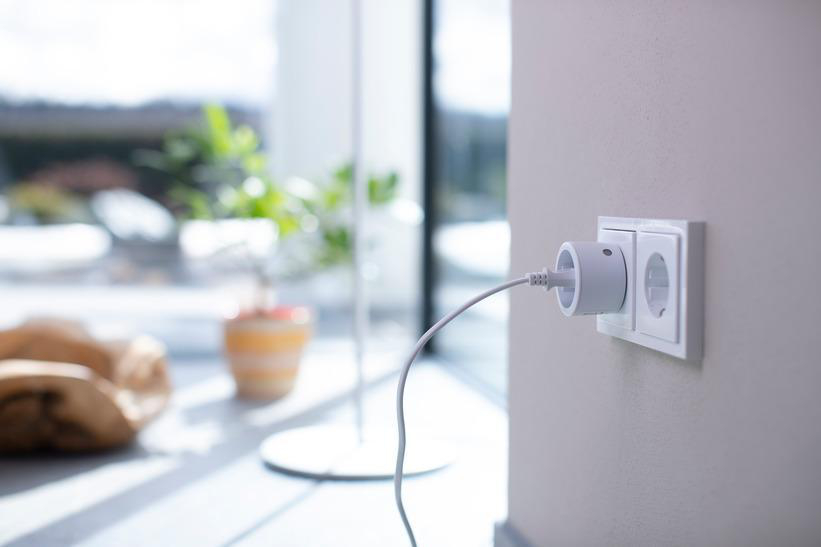 Weißer Smart Plug in einer Steckdose. Ein Kabel erstreckt sich vom Stecker aus.