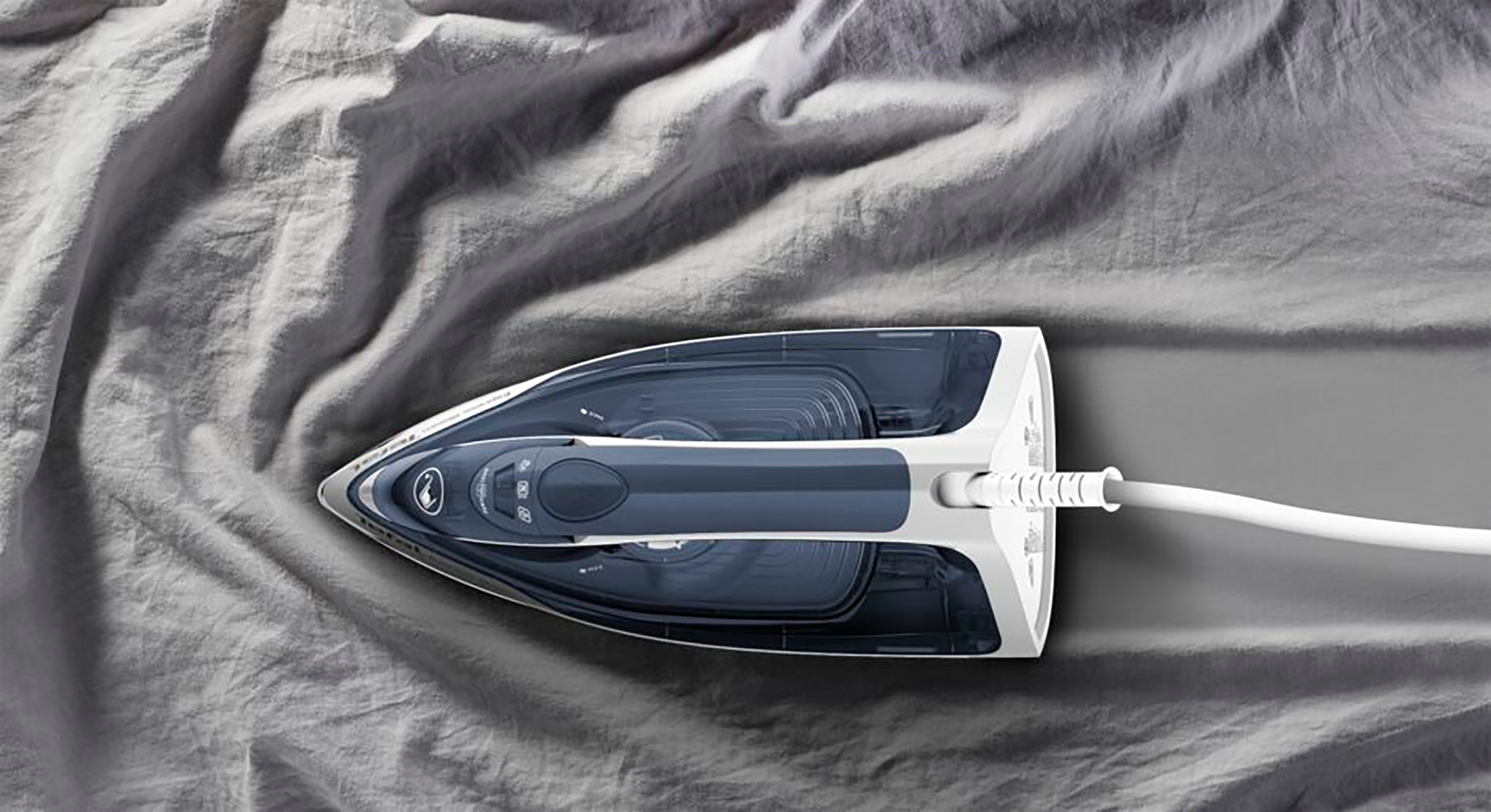 An iron on gray wrinkled fabric. The iron is white and navy blue, positioned on the fabric.