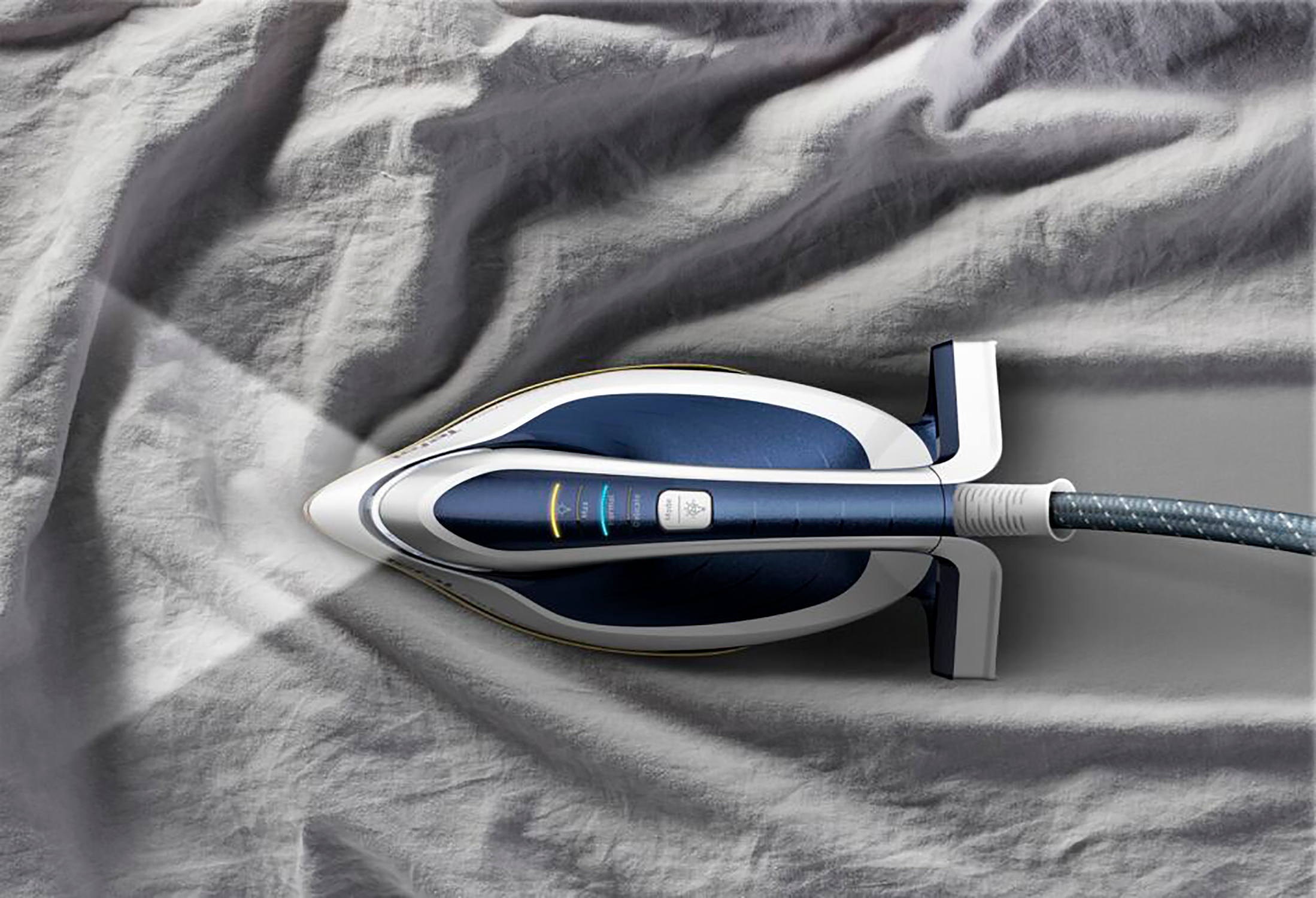 Ironing machine on gray fabric, steam emitting. Dark blue and white with the handle.