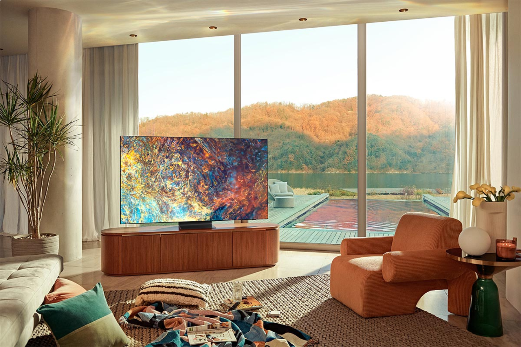 Salón con TV, sofá, sillón y ventana con vistas a un lago.
