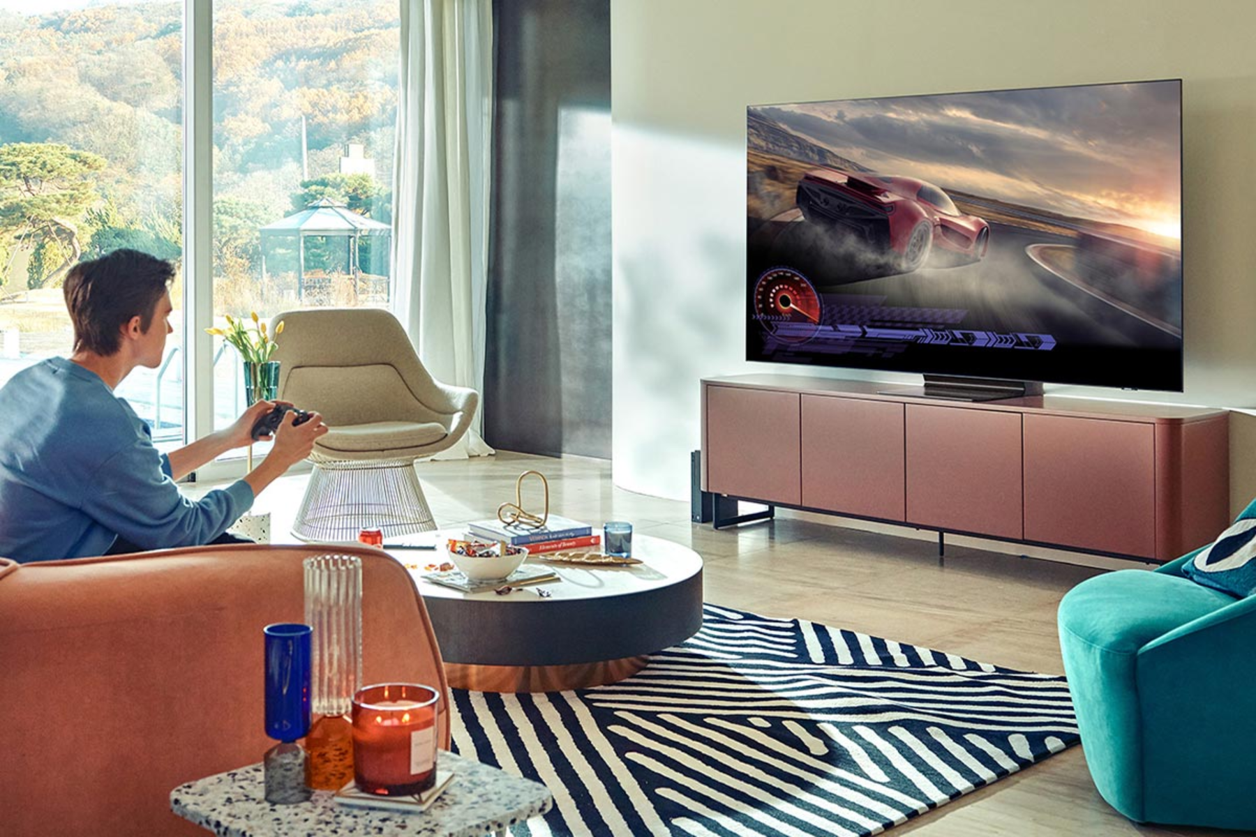 Escena de sala de estar con persona jugando videojuegos en TV grande. Muebles modernos, iluminación brillante.