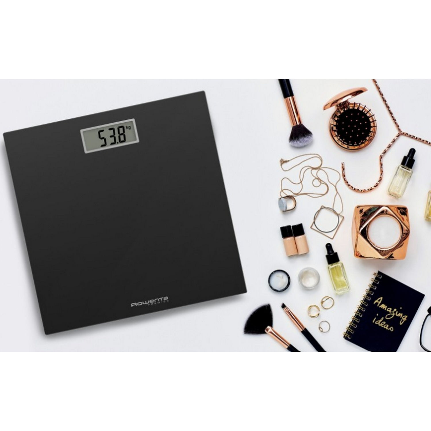 Báscula digital negra con pantalla de peso. Artículos de maquillaje y accesorios están alrededor de la báscula sobre una superficie blanca.