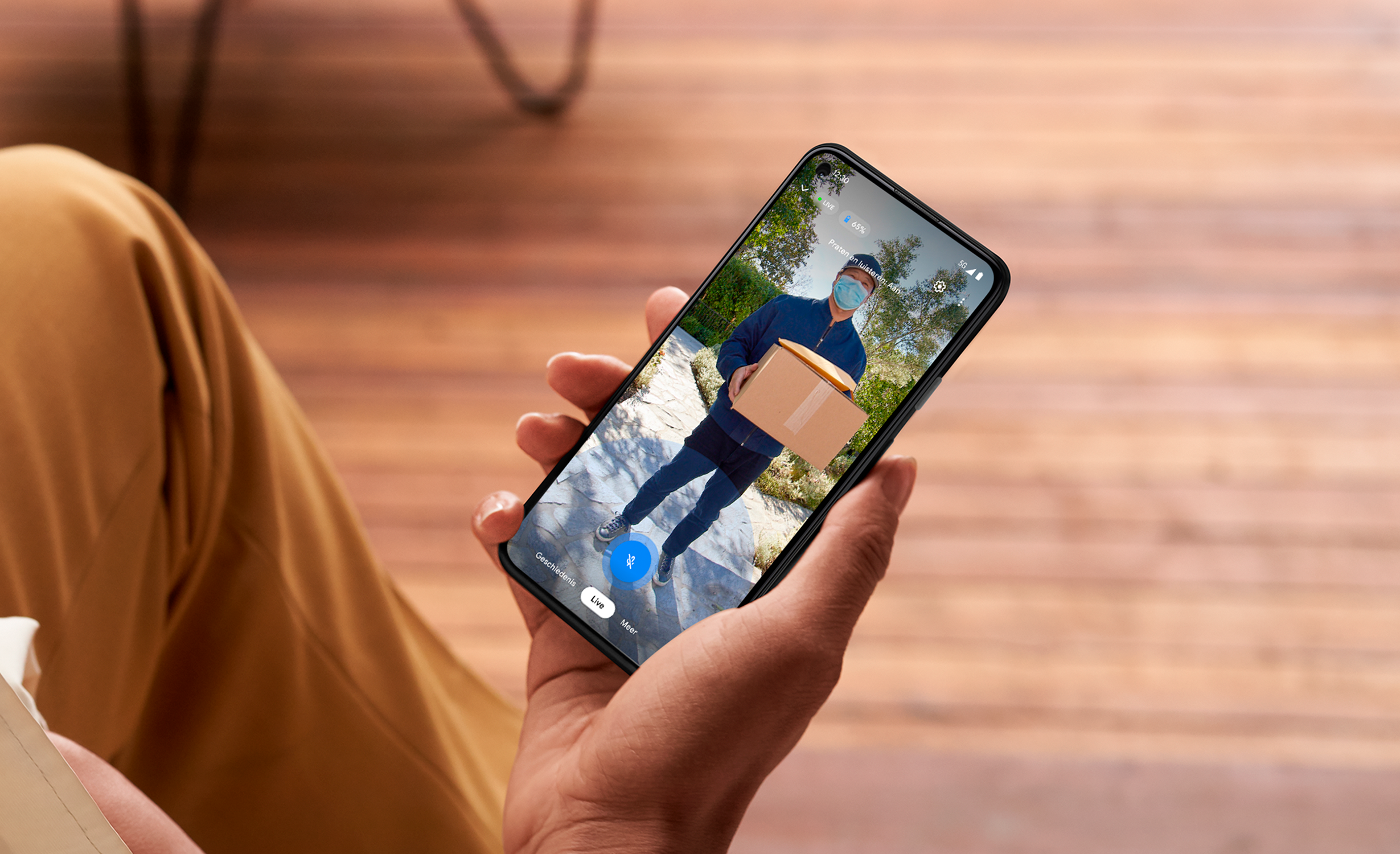 Een persoon die een telefoon vasthoudt met een bezorger. De persoon draagt een masker.