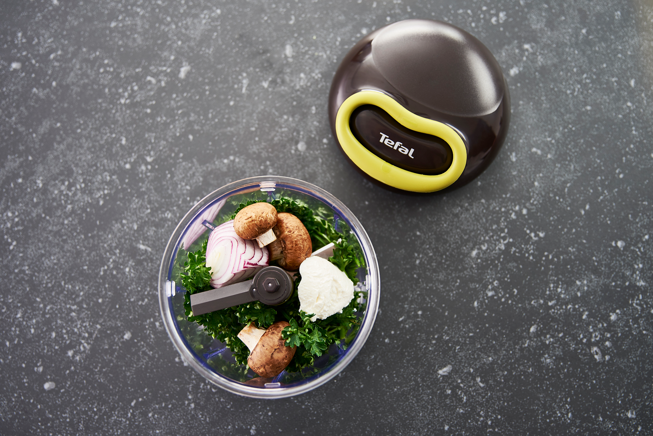 A Tefal chopper with vegetables on a dark surface.