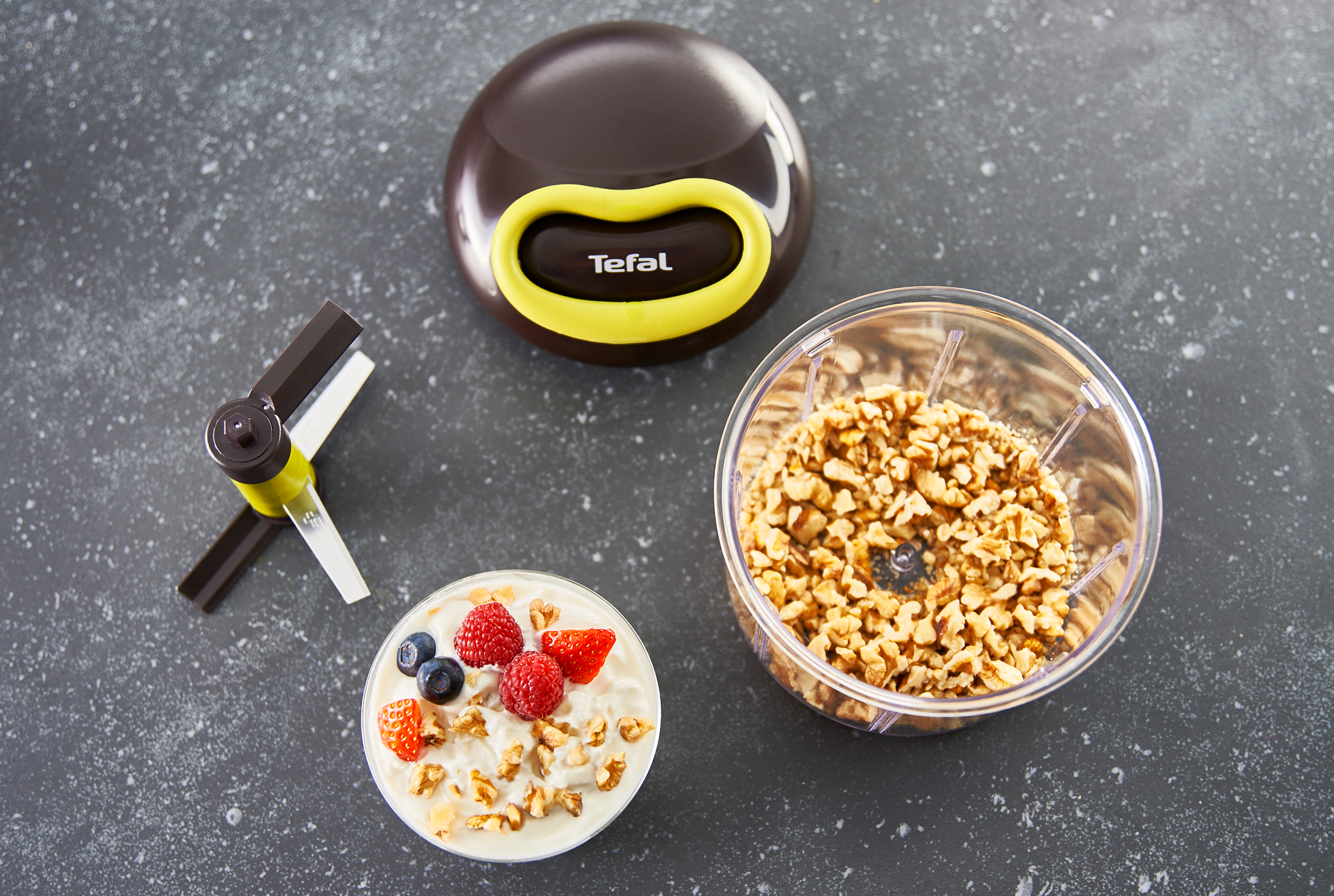 A Tefal chopper with chopped walnuts, a bowl of yogurt with berries, and the chopper's blade assembly.